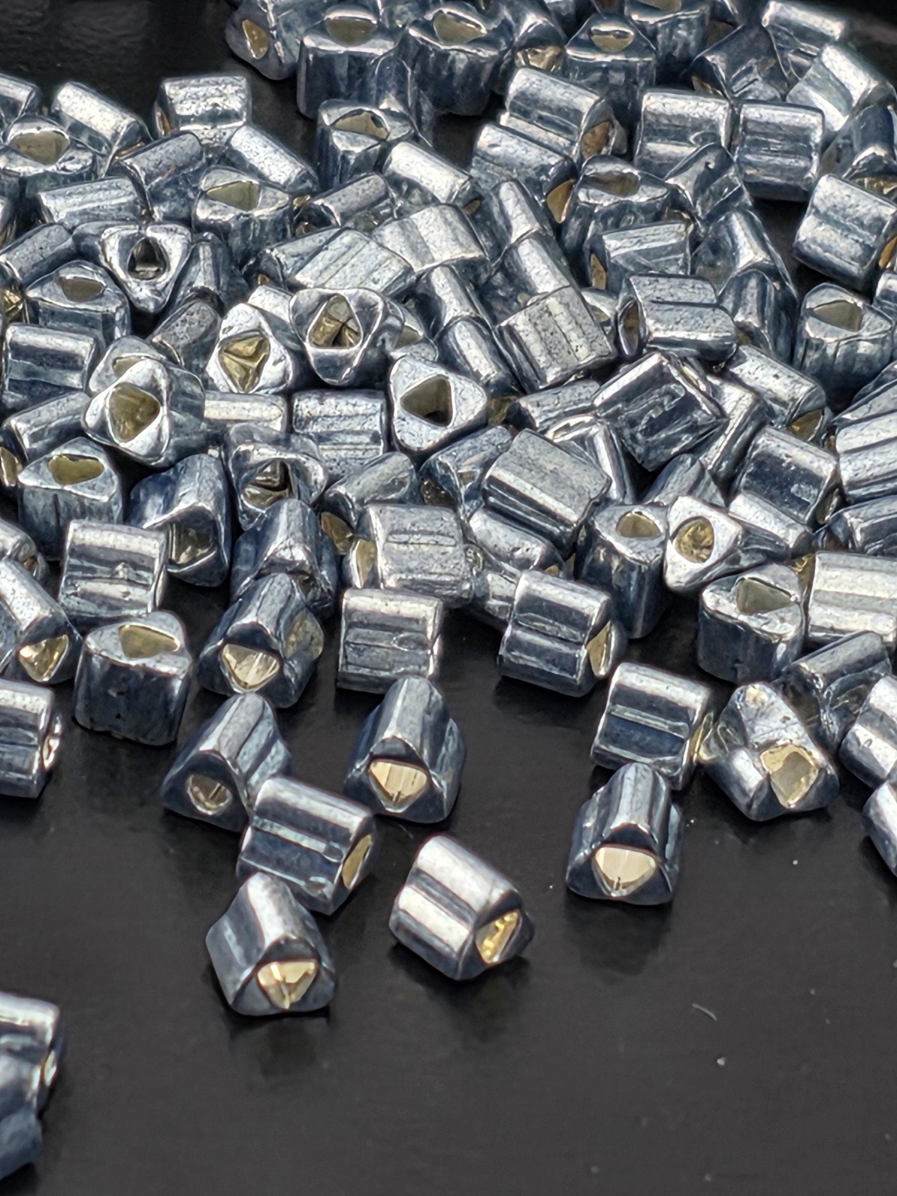 a close-up view of numerous small, metallic beads or pieces scattered on a dark surface.