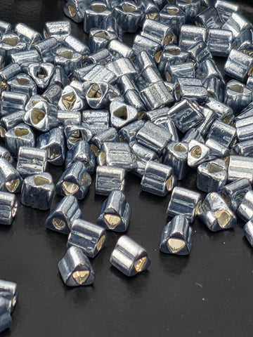 a close-up view of numerous small, metallic beads or pieces scattered on a dark surface.