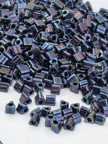 a close-up view of numerous small, square-shaped beads in various shades of blue, scattered across a white surface.