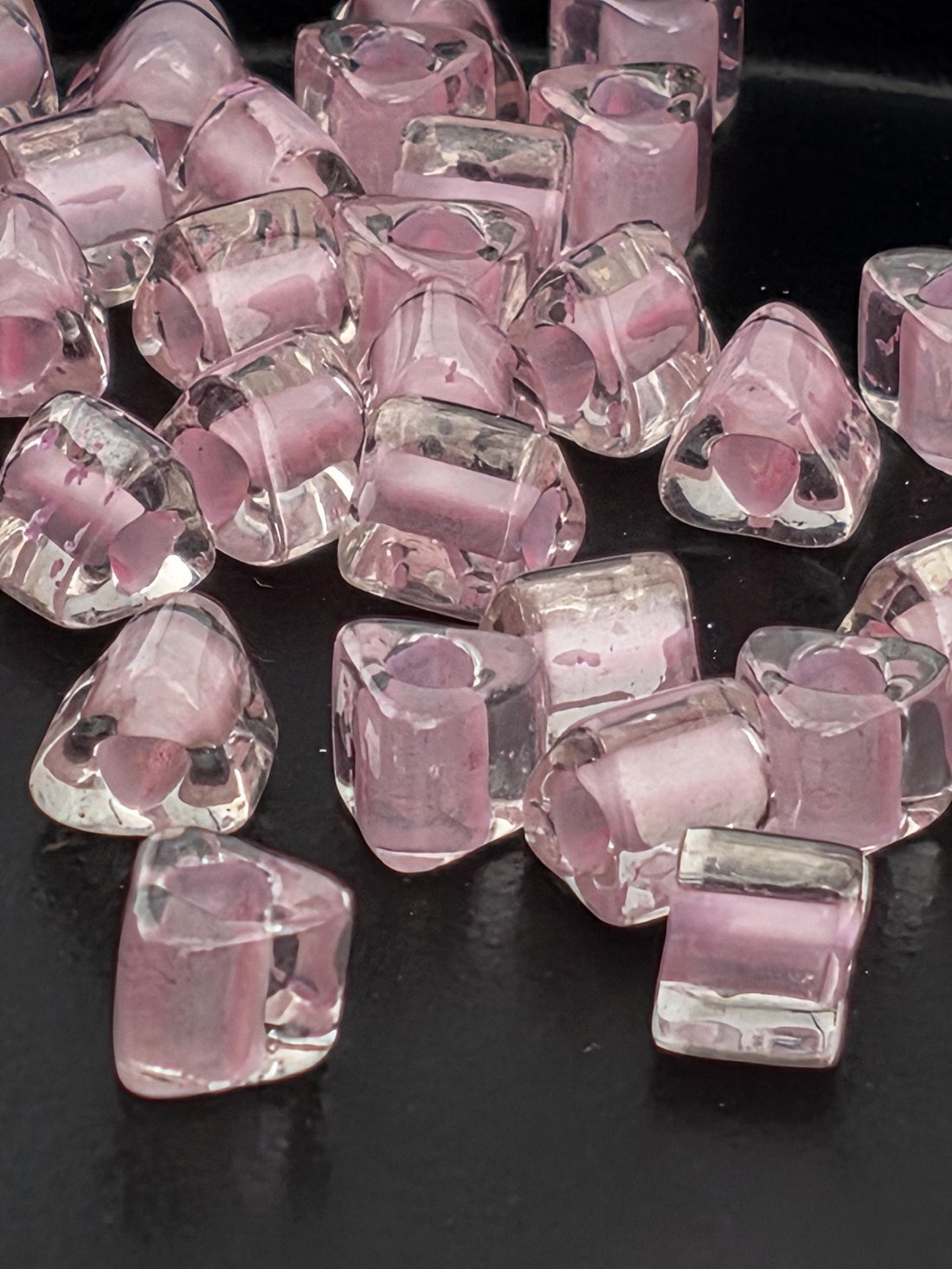 a collection of clear, transparent glass beads scattered on a dark background.