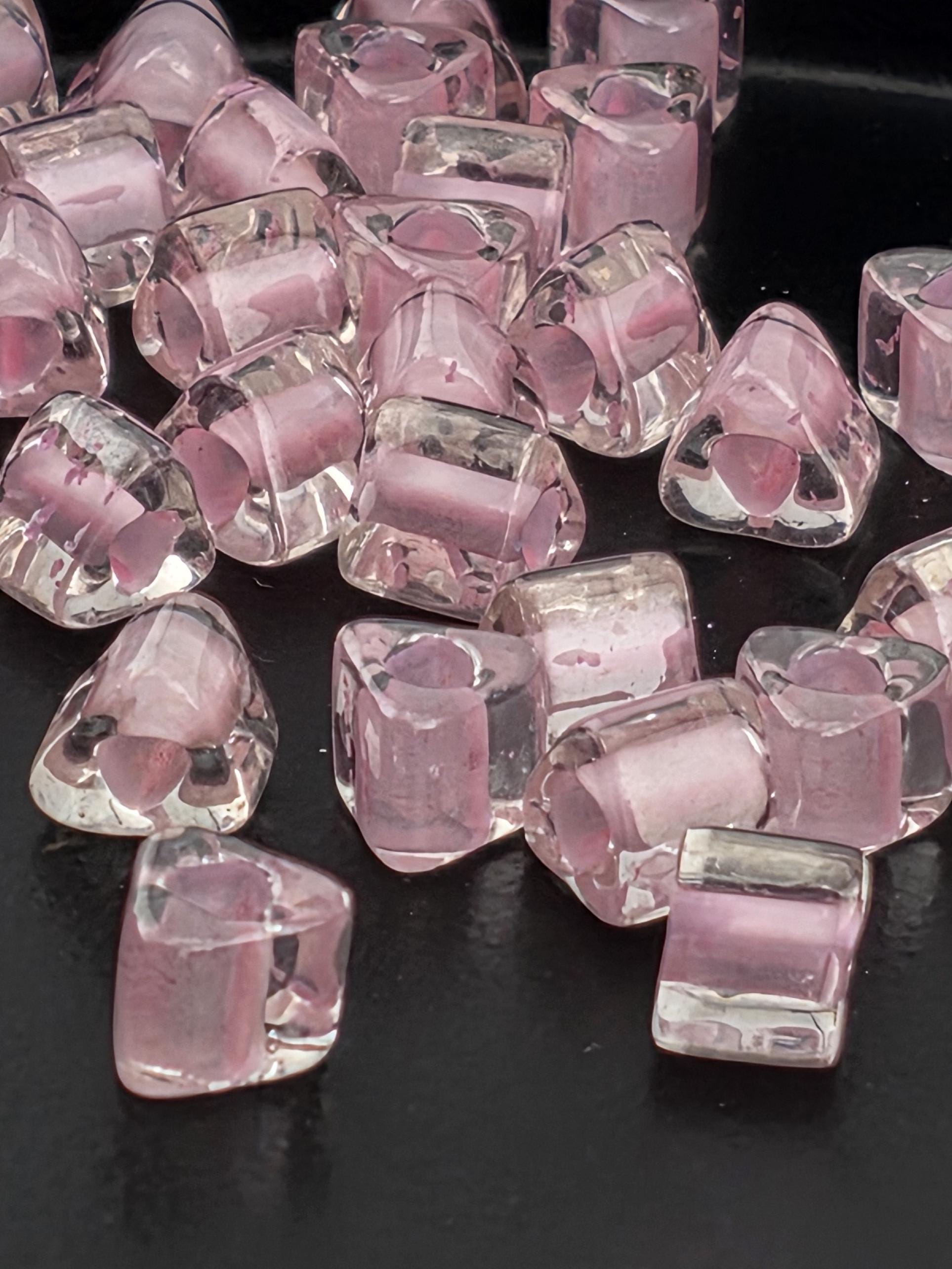 a collection of clear, transparent glass beads scattered on a dark background.