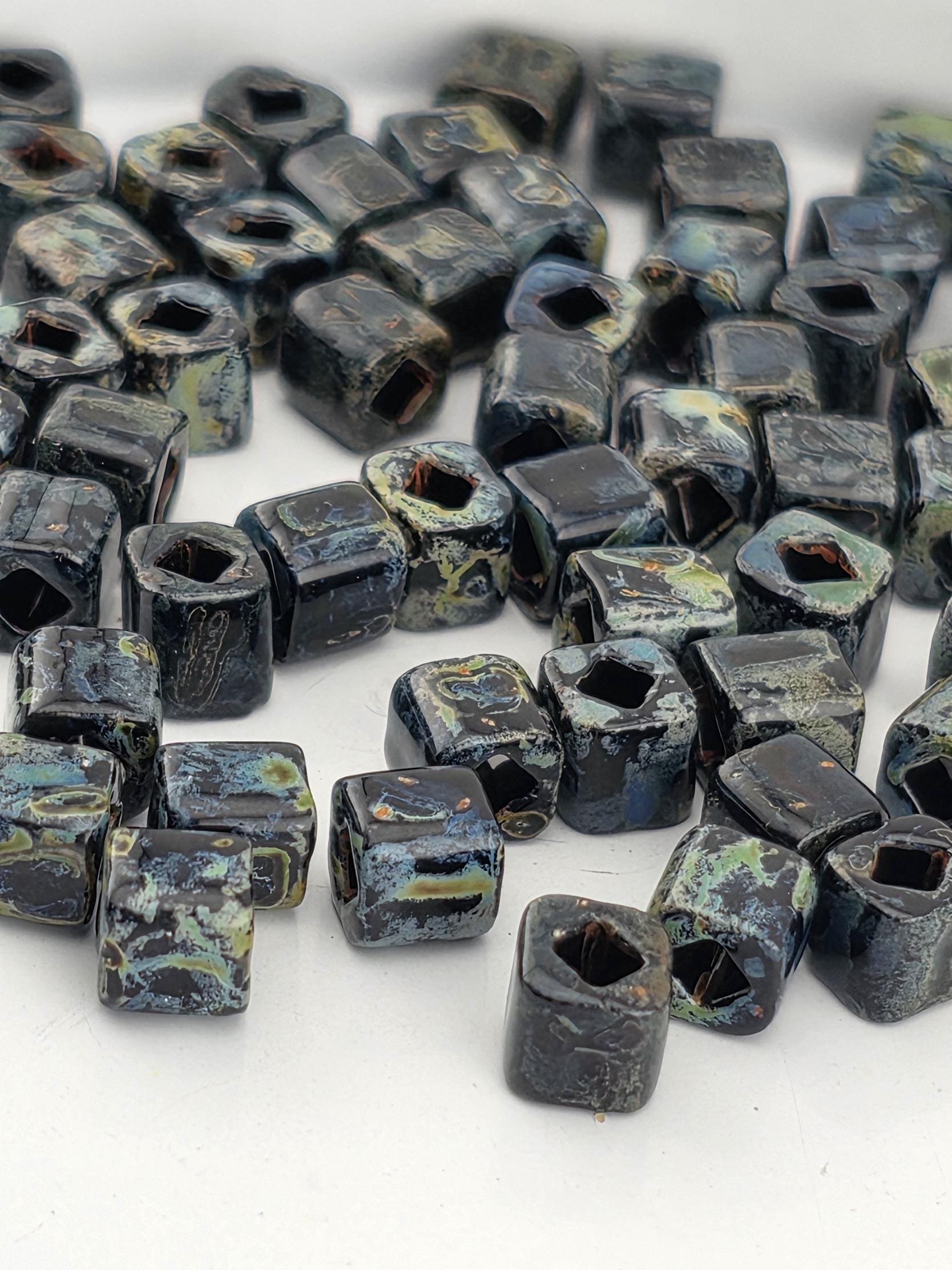 a collection of small, square-shaped objects with a dark, textured appearance. The objects are scattered across a white surface, creating a visually striking contrast.