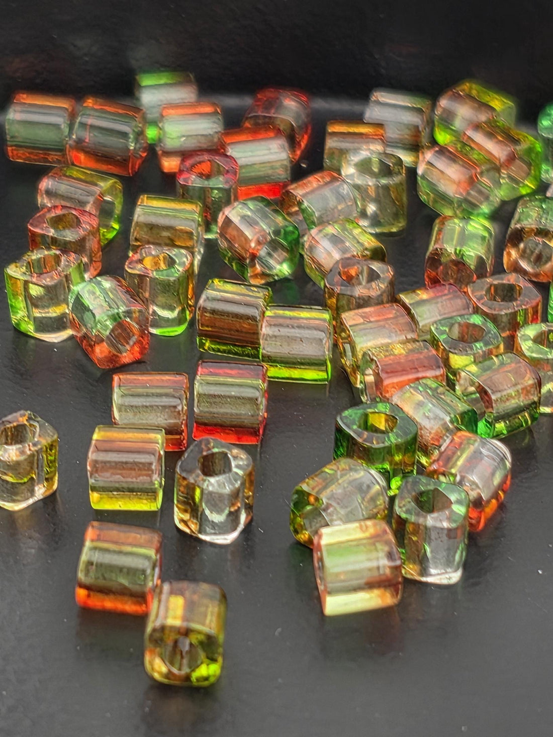a collection of colorful glass beads scattered on a dark surface.