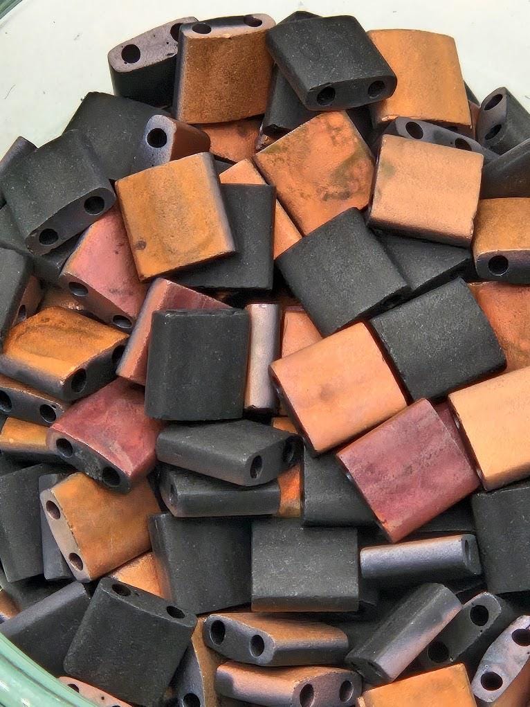 A pile of various colored beads, including black, orange, and red, arranged in a visually appealing manner.