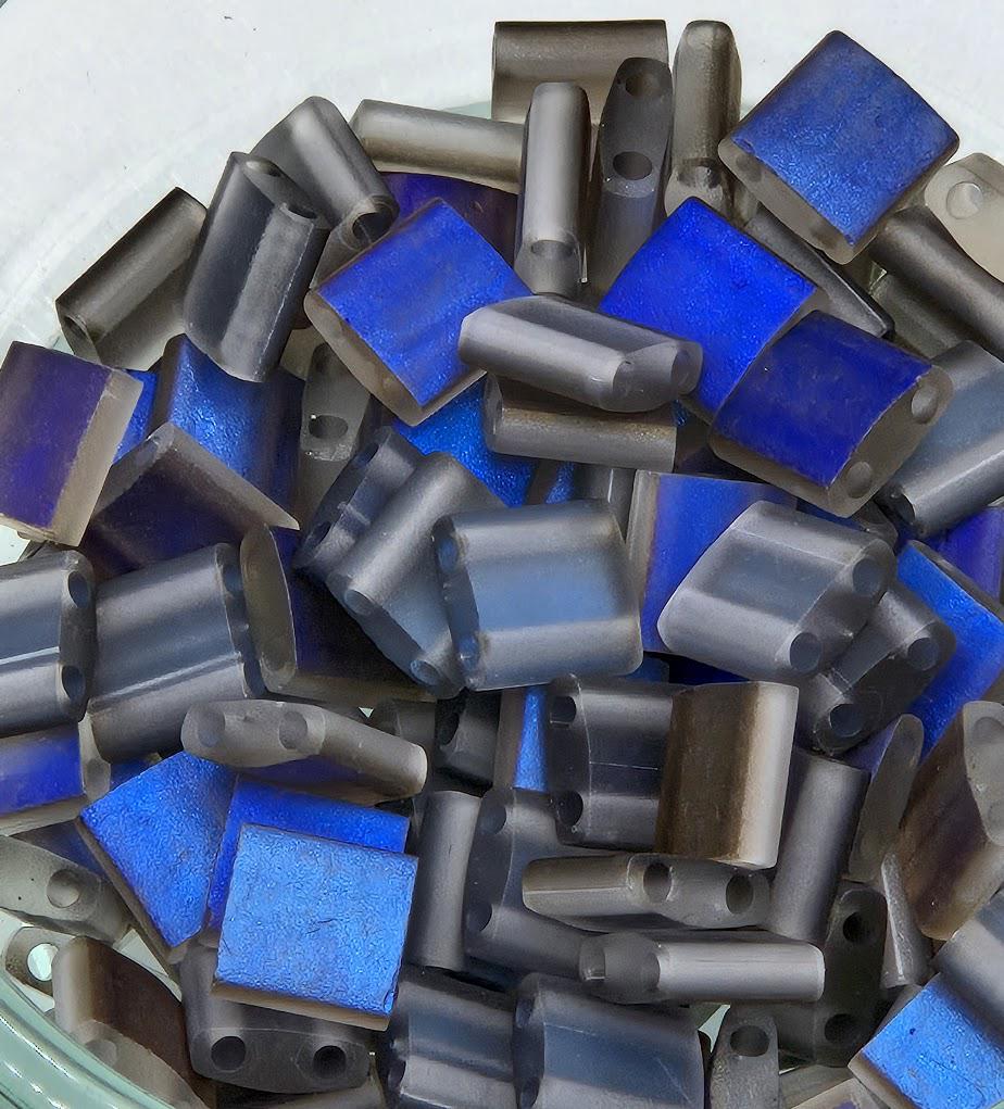 a collection of various metal objects, including rods and tubes, in shades of blue and gray. The objects appear to be made of metal and are arranged in a pile or container.