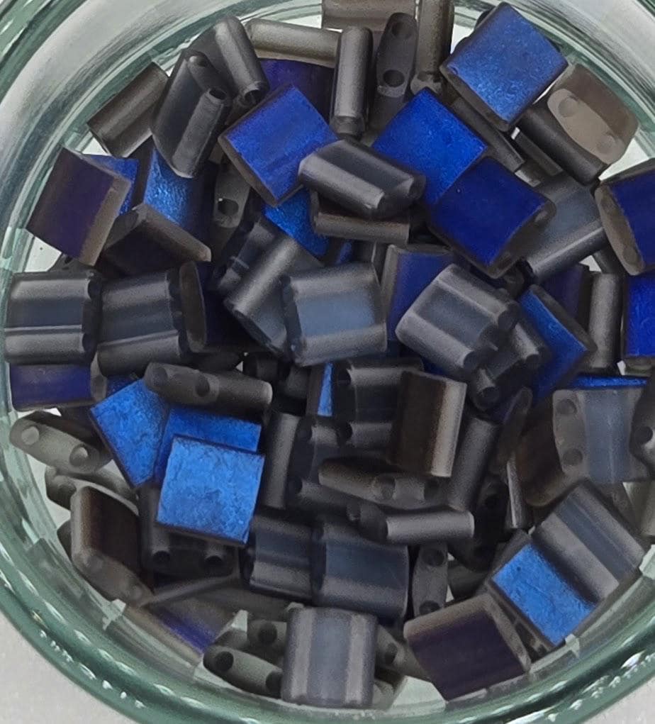 A glass jar filled with various blue and gray glass beads or pieces.
