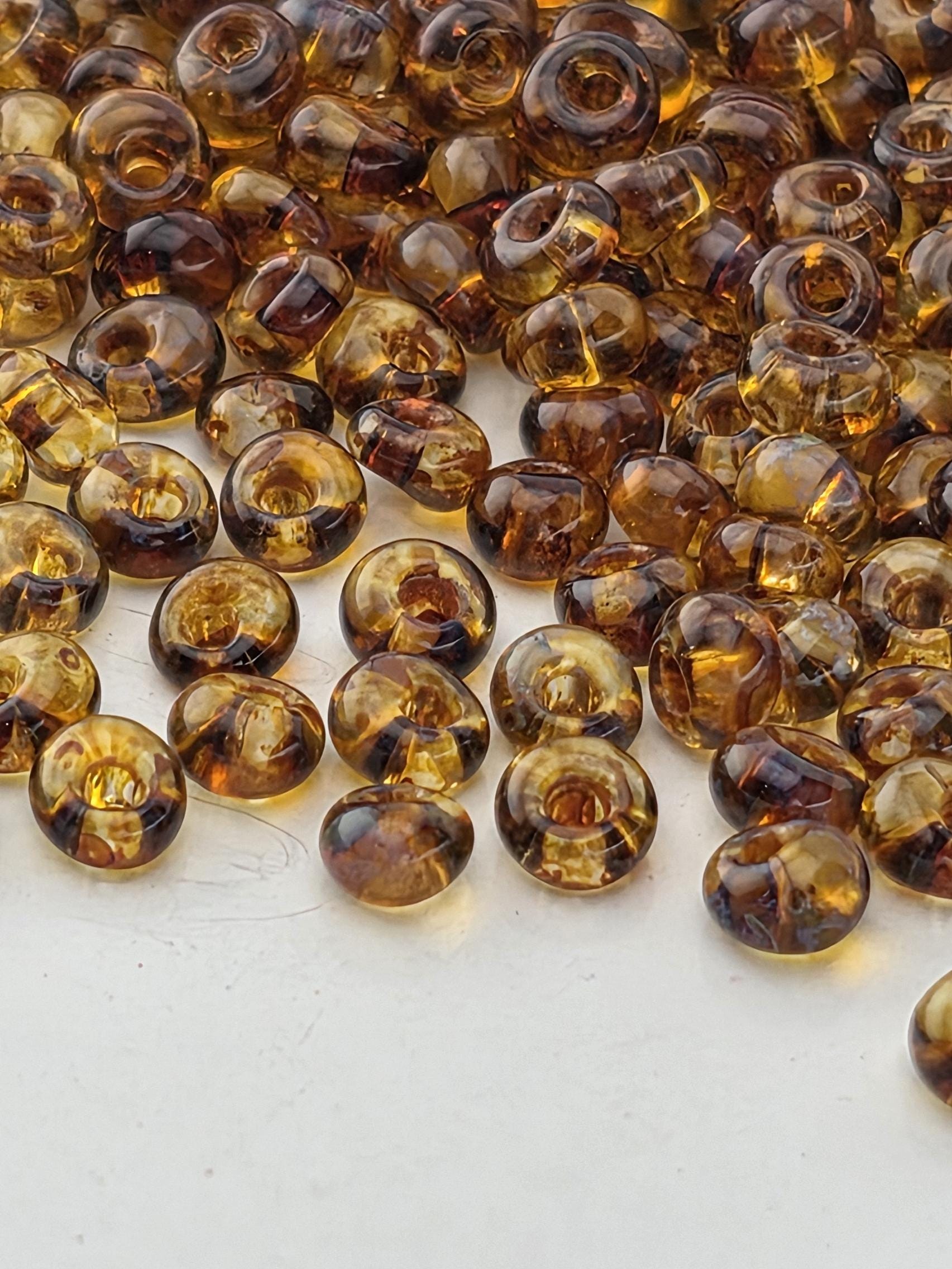 a close-up view of numerous small, round, brown glass beads scattered across a white surface.