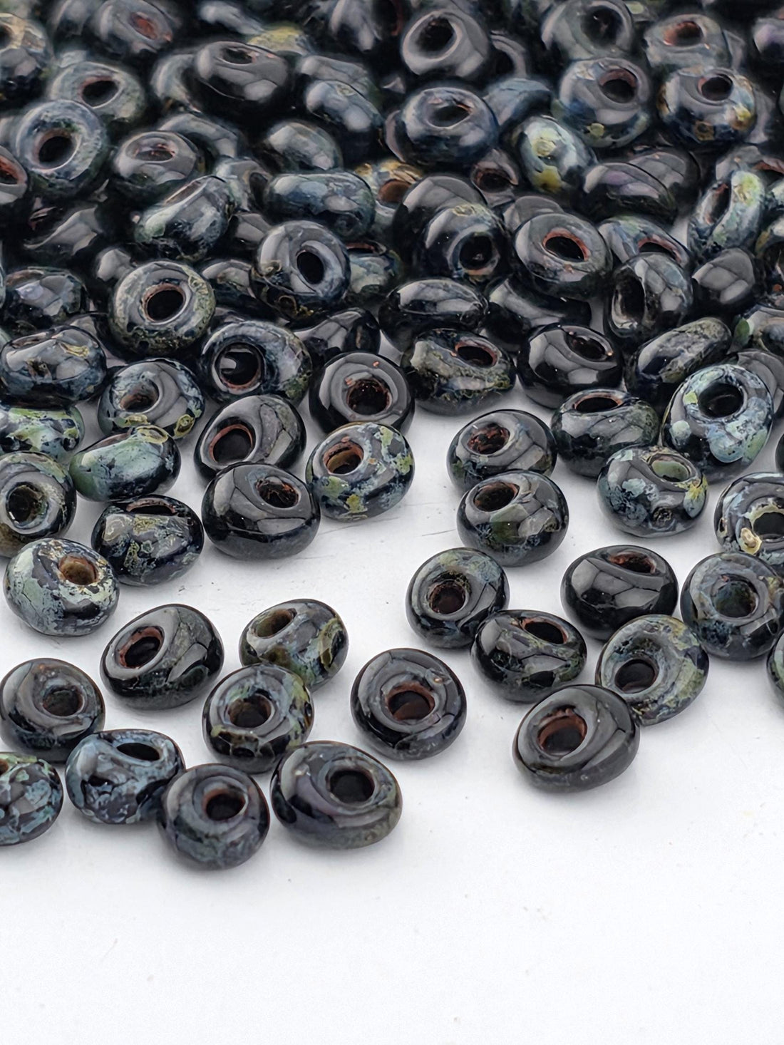 a collection of black and green beads scattered on a white background.