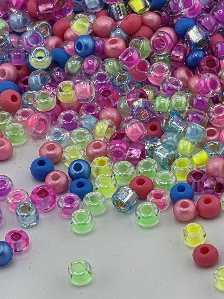 A colorful assortment of multicolored beads, including clear, blue, pink, and yellow beads, scattered across a surface.