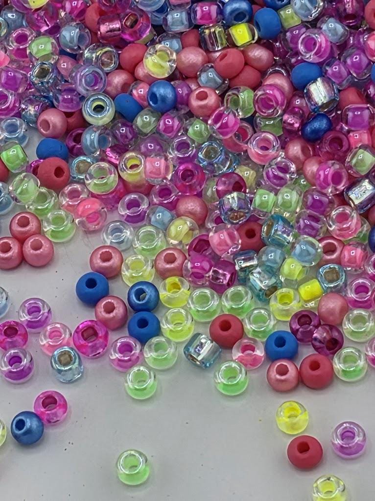 A colorful assortment of multicolored beads, including clear, blue, pink, and yellow beads, scattered across a surface.