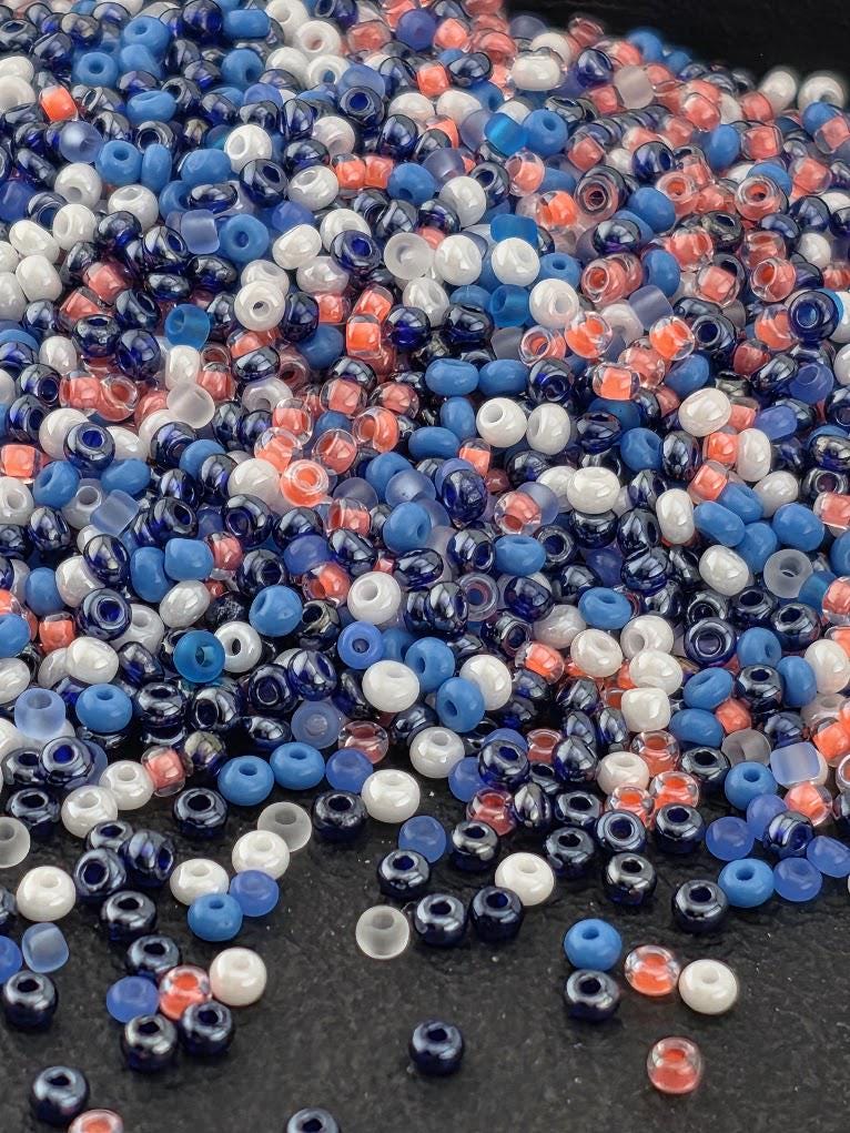 A pile of multicolored beads, including blue, white, and red, scattered on a dark surface.