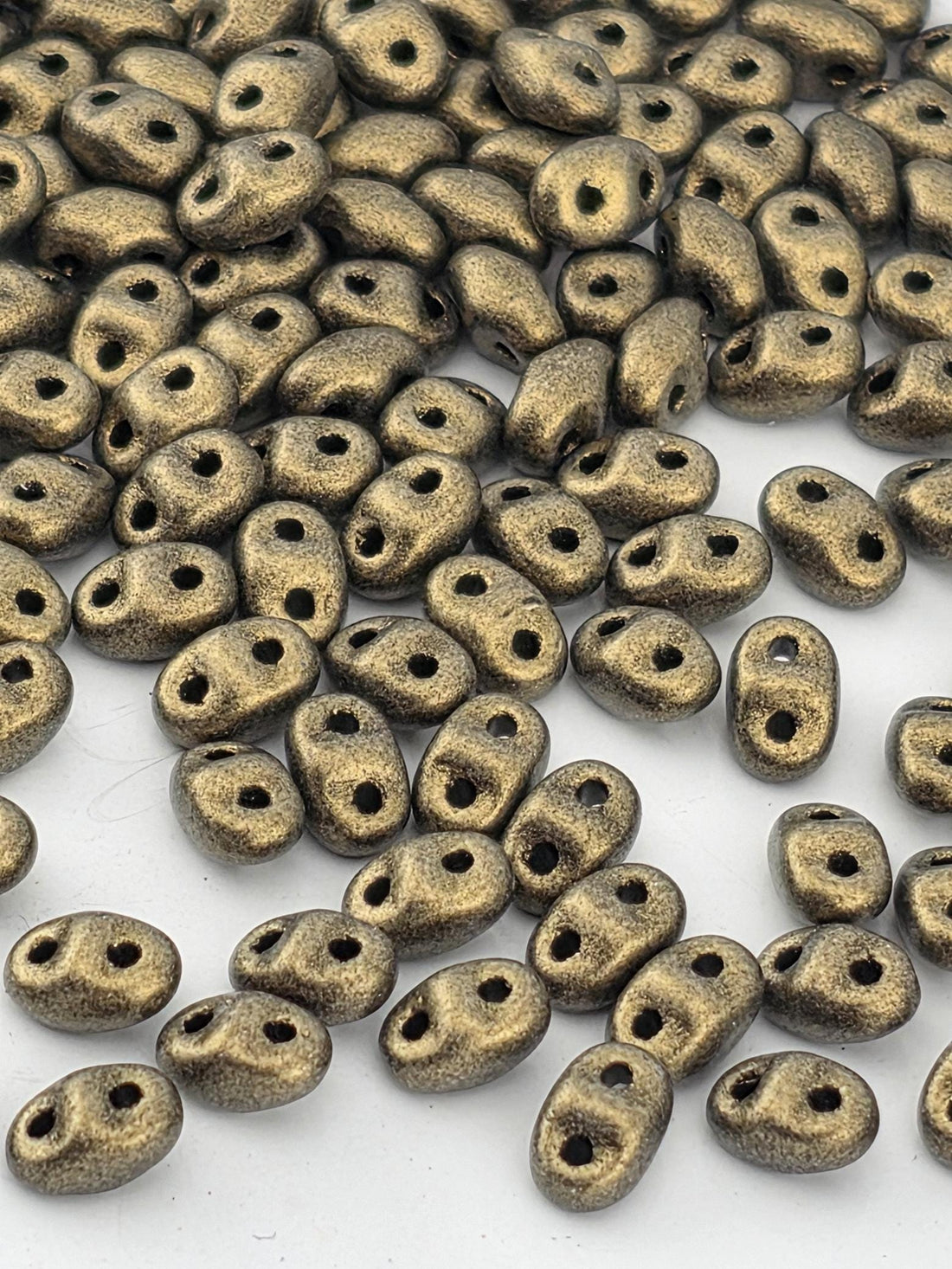 a collection of small, shiny, and metallic beads scattered across a white background.