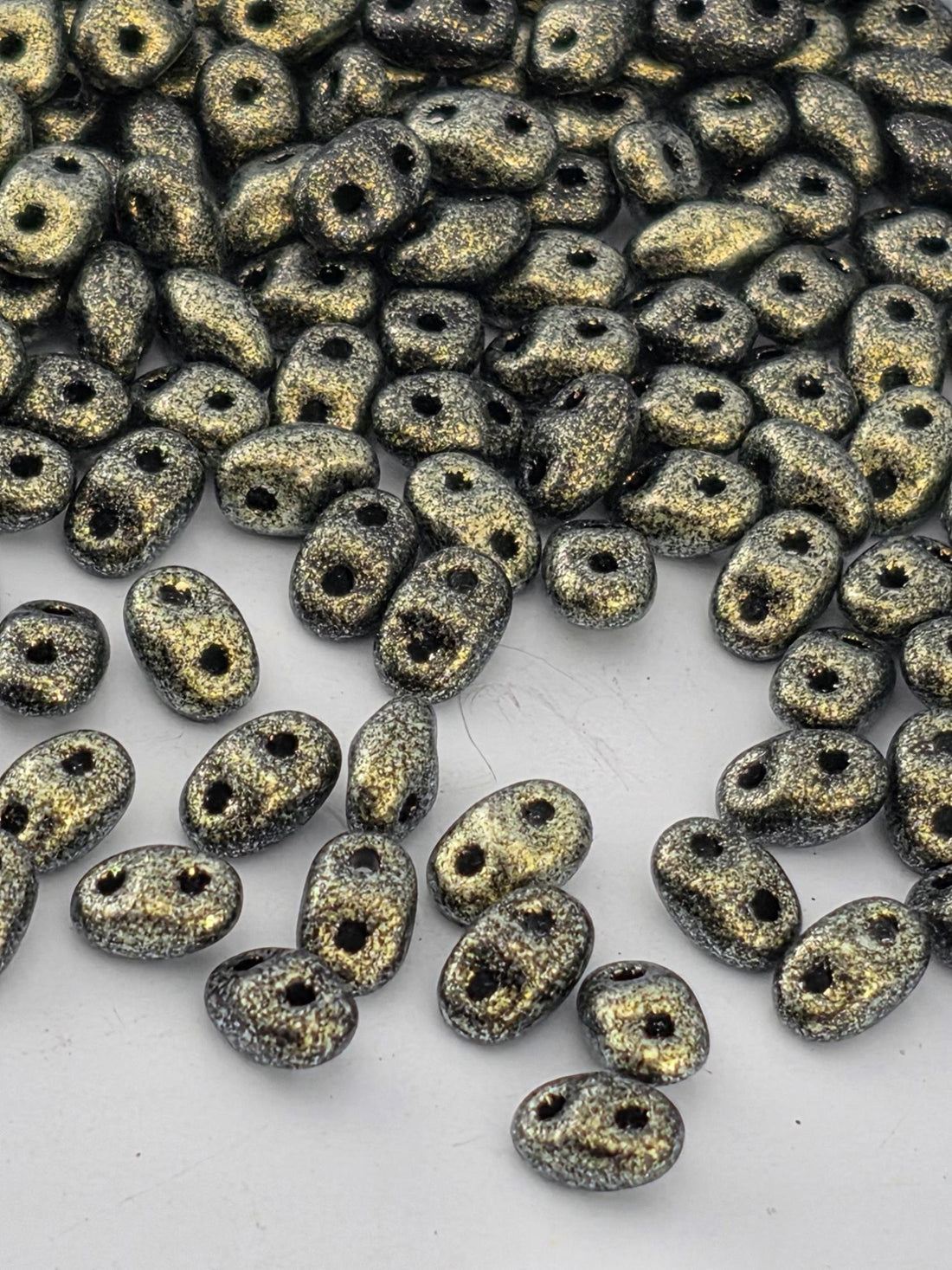 a collection of small, shiny, and metallic beads scattered across a white background.