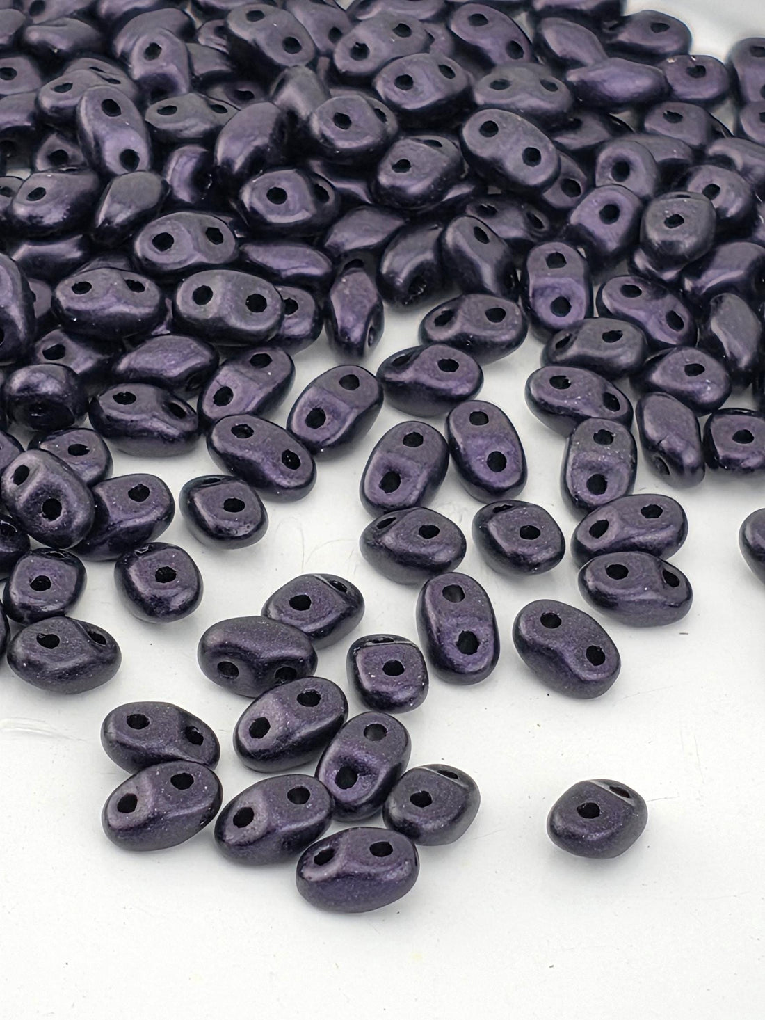a collection of small, purple beads scattered on a white surface.
