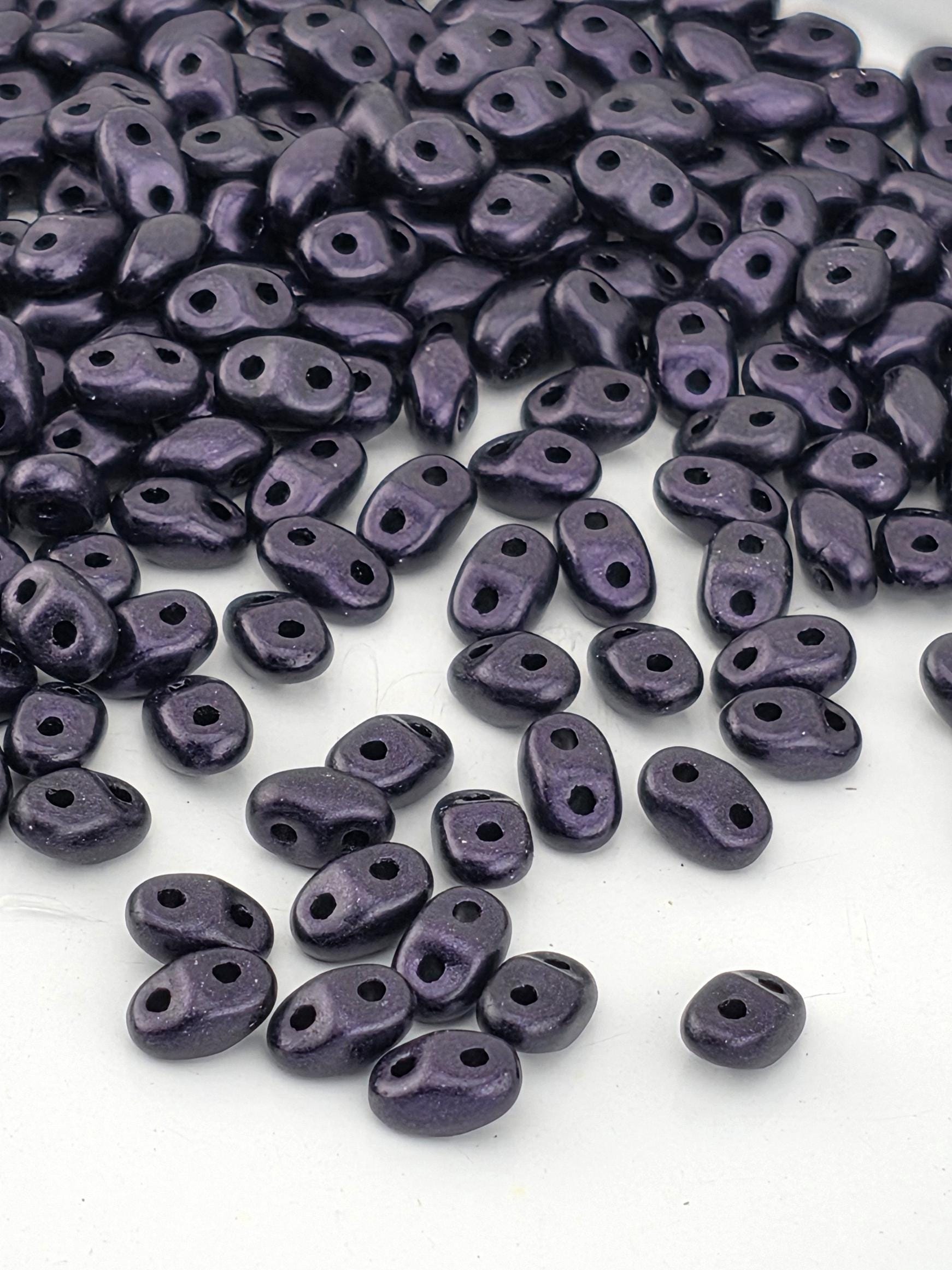a collection of small, purple beads scattered on a white surface.