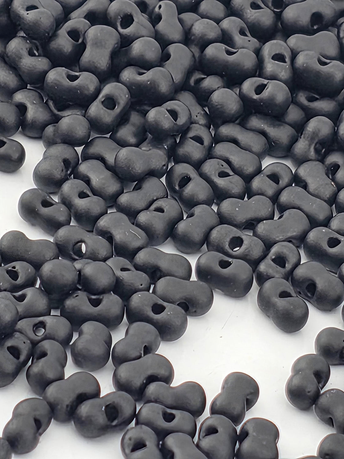 a collection of black beads or objects scattered on a white surface.
