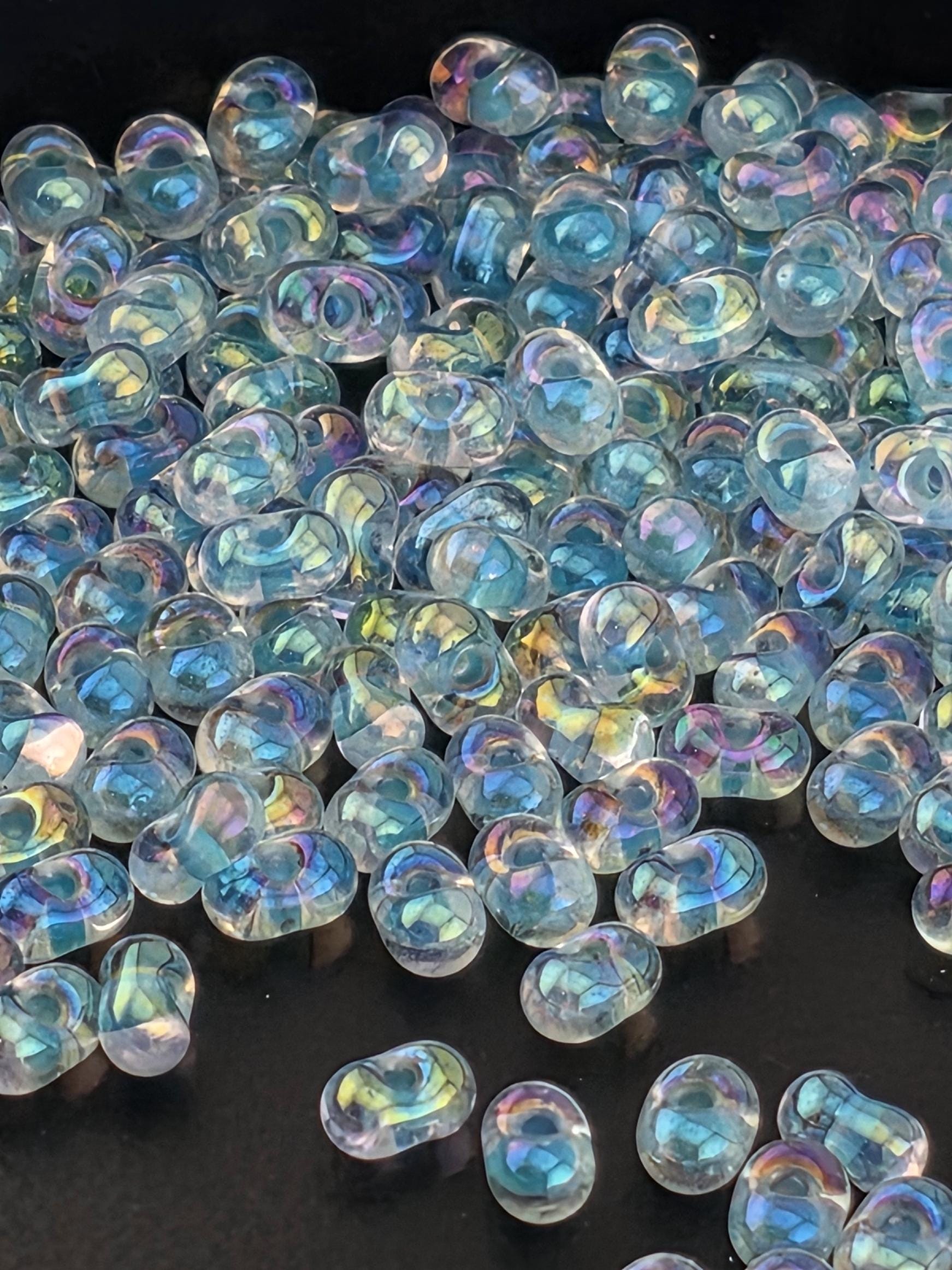 a close-up view of numerous transparent, iridescent beads scattered across a dark background.