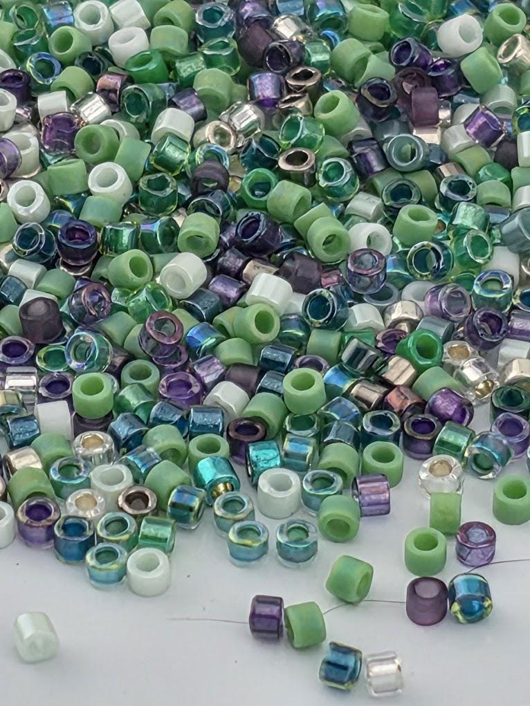 The image is a collection of various colored beads, including green, purple, and white, scattered across a surface.