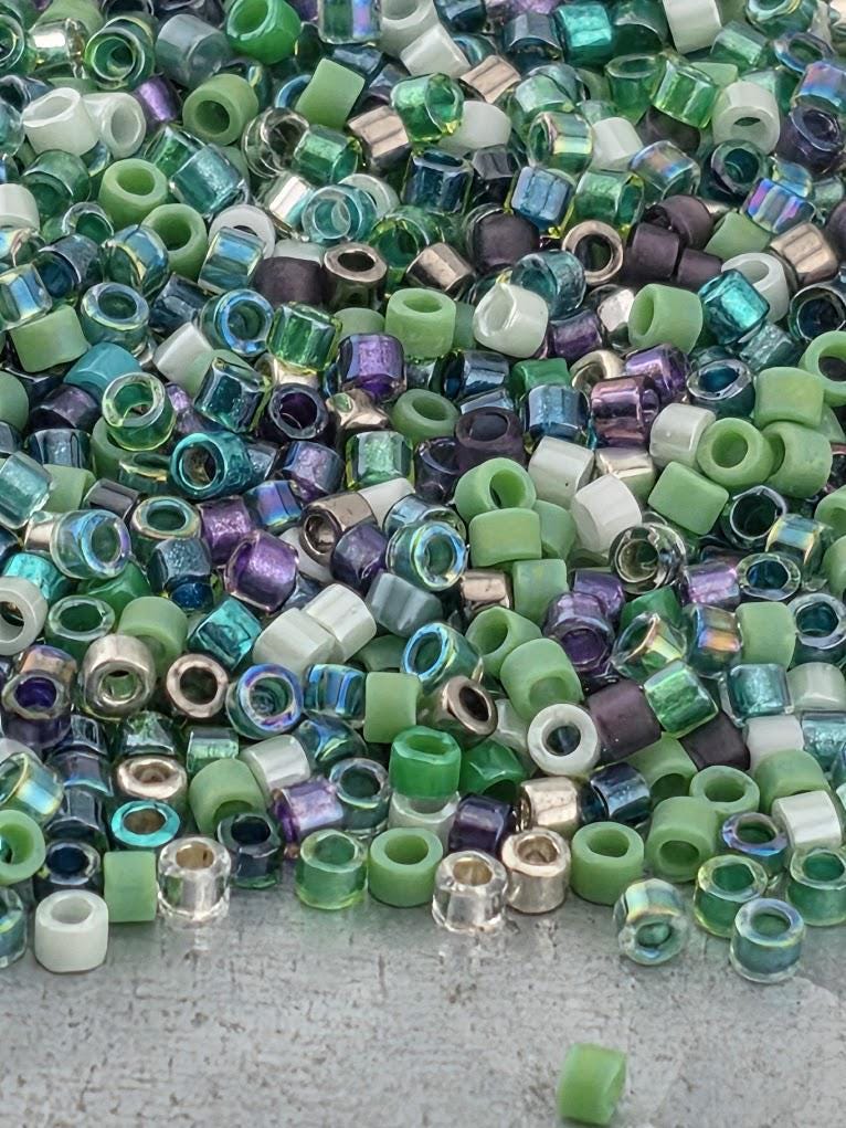 A large pile of multicolored glass beads, including various shades of green, purple, and white, scattered on a surface.