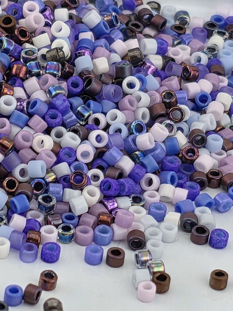 A colorful pile of multicolored beads, including white, purple, blue, and brown, scattered on a surface.