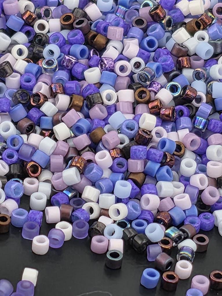 A colorful assortment of multicolored beads, including purple, blue, and white, scattered across a dark surface.