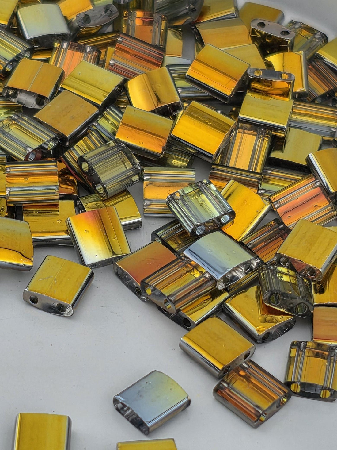 numerous small, square-shaped objects with a metallic, reflective appearance, scattered across a surface.