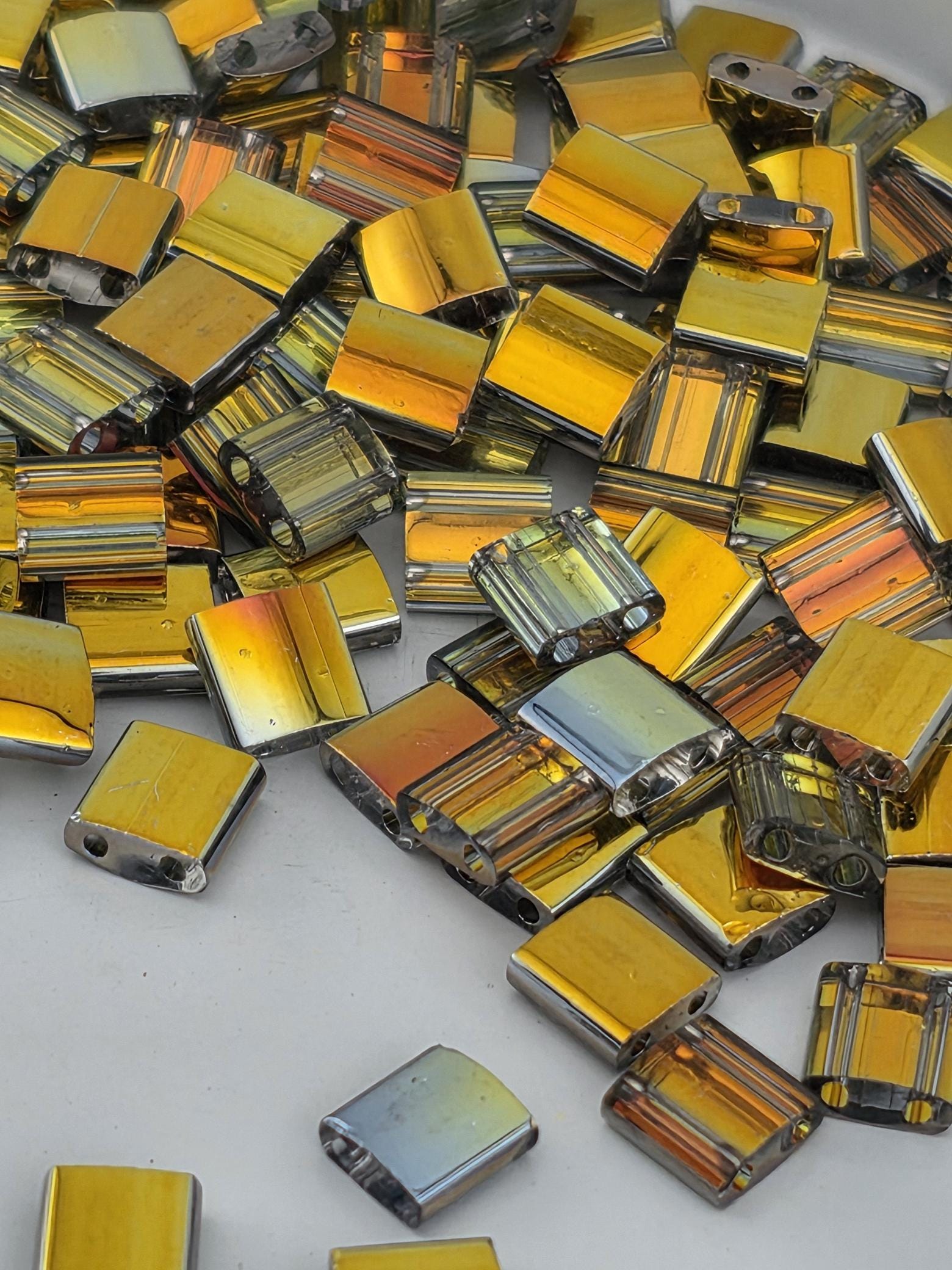 numerous small, square-shaped objects with a metallic, reflective appearance, scattered across a surface.