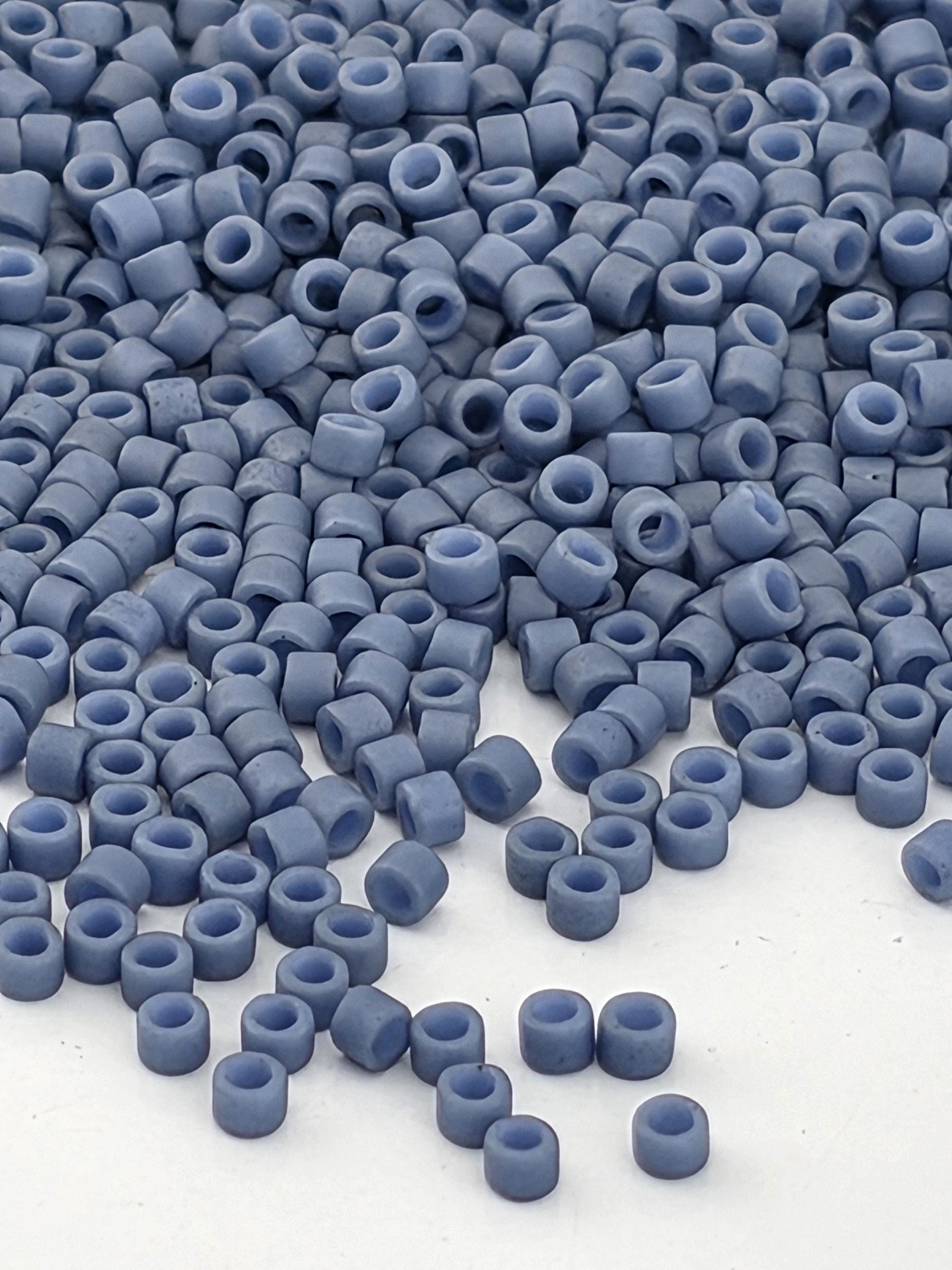 a close-up view of numerous small, round beads in various shades of blue, scattered across a white surface.