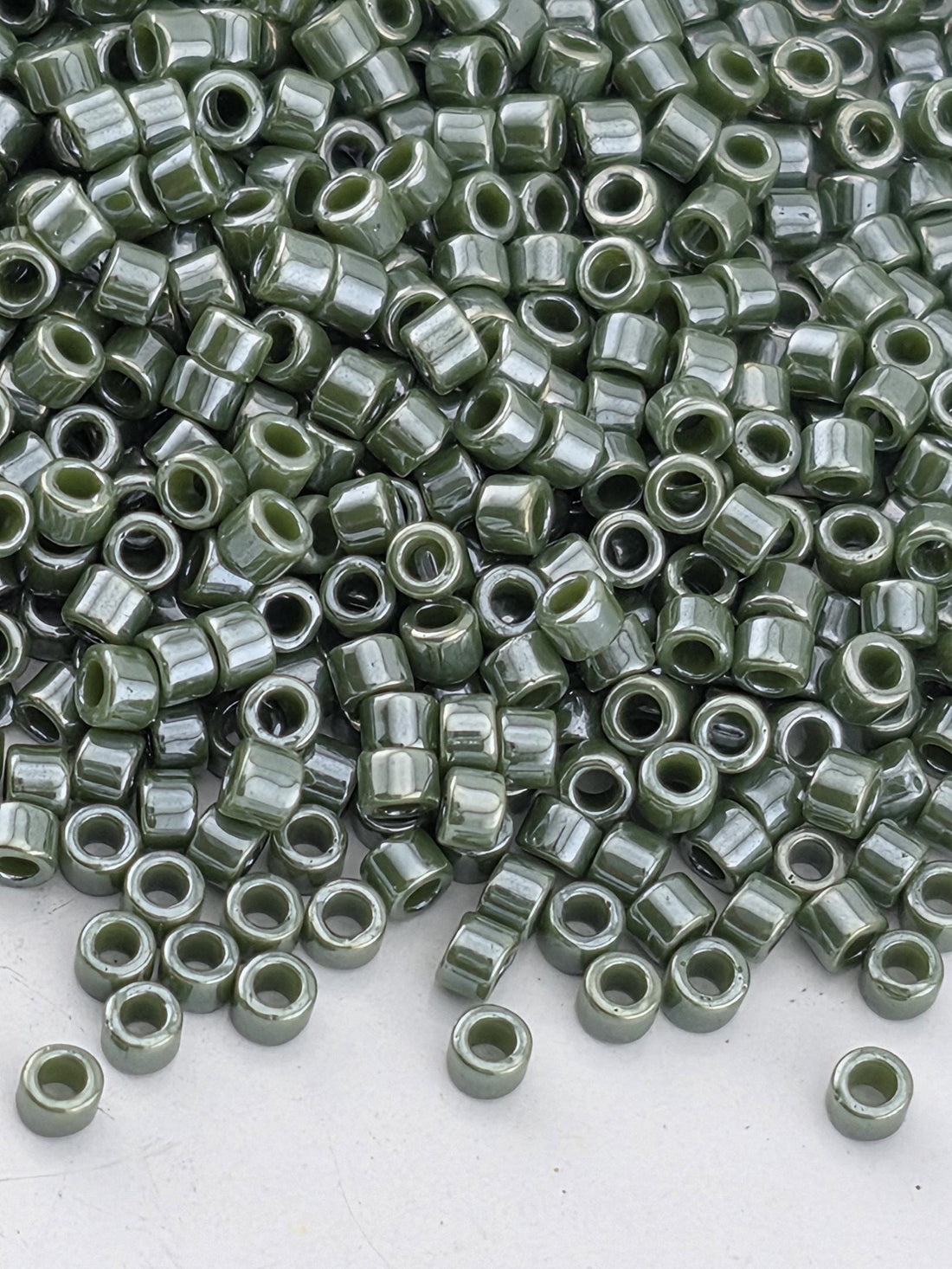 a large pile of green glass beads or buttons scattered on a white surface.