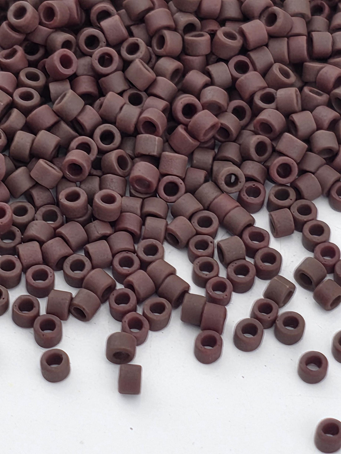 a large pile of brown beads or objects scattered on a white surface.