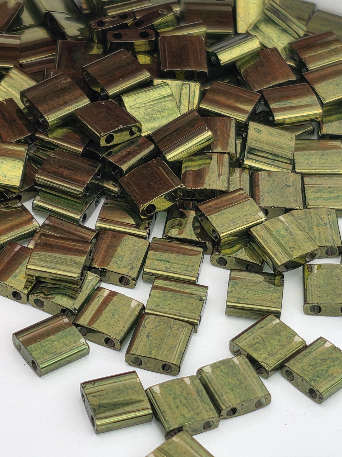 numerous small, square-shaped objects with a greenish-brown hue, scattered across a white background.