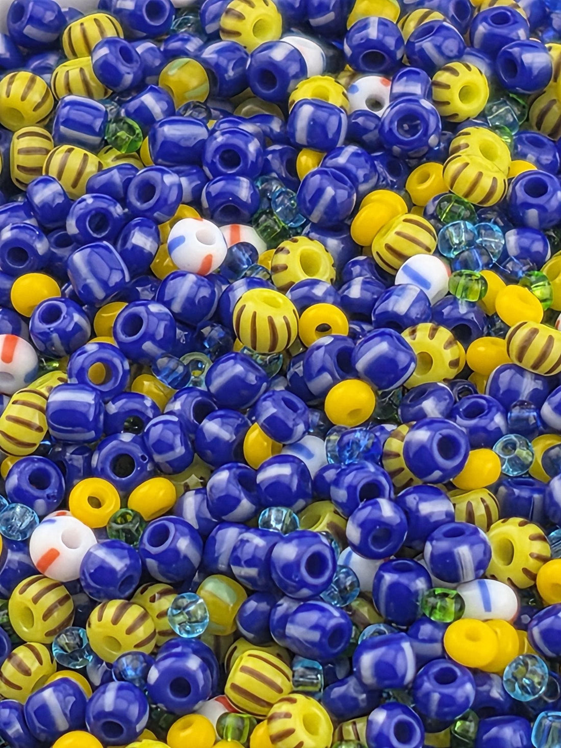 A colorful assortment of beads in various shapes and sizes, including blue, yellow, and multicolored beads, creating a vibrant and playful visual.