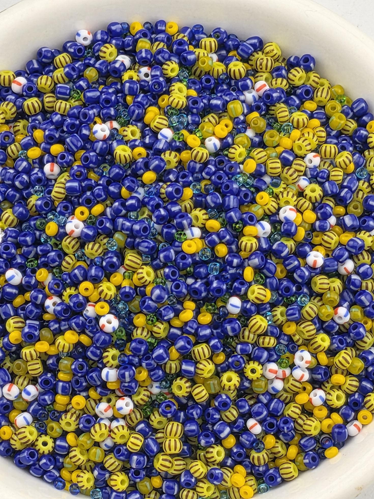 A bowl filled with colorful beads in various shades of blue, yellow, and red.