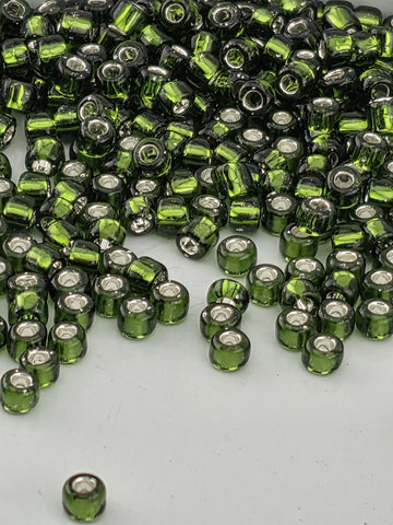 a large pile of green glass beads scattered on a white surface.