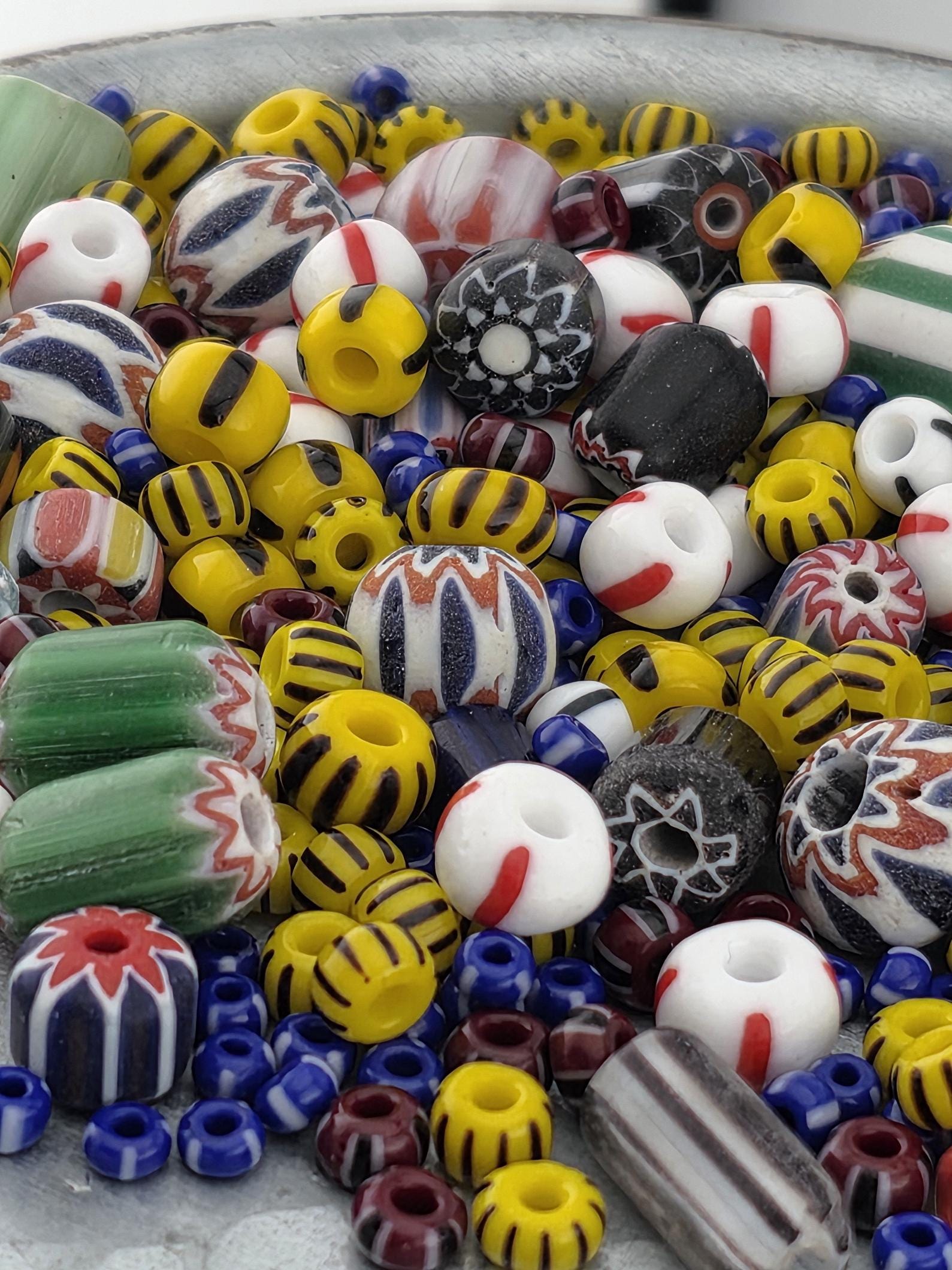 A colorful assortment of beads, including glass beads in various colors and patterns, is scattered across a surface.