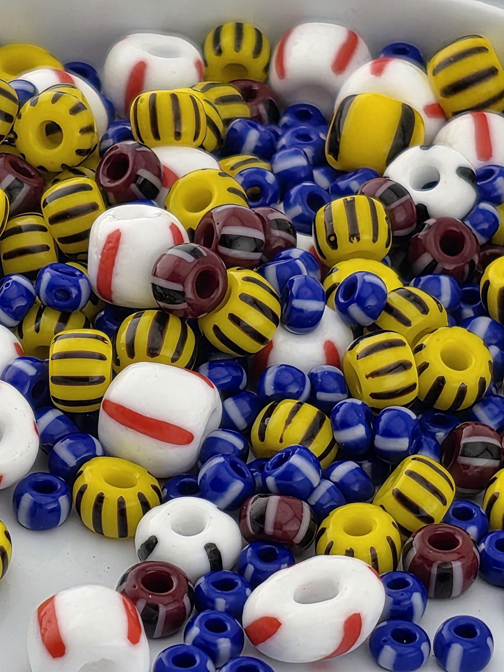 A colorful assortment of beads in various shapes and sizes, including yellow, blue, red, and white beads, scattered together.