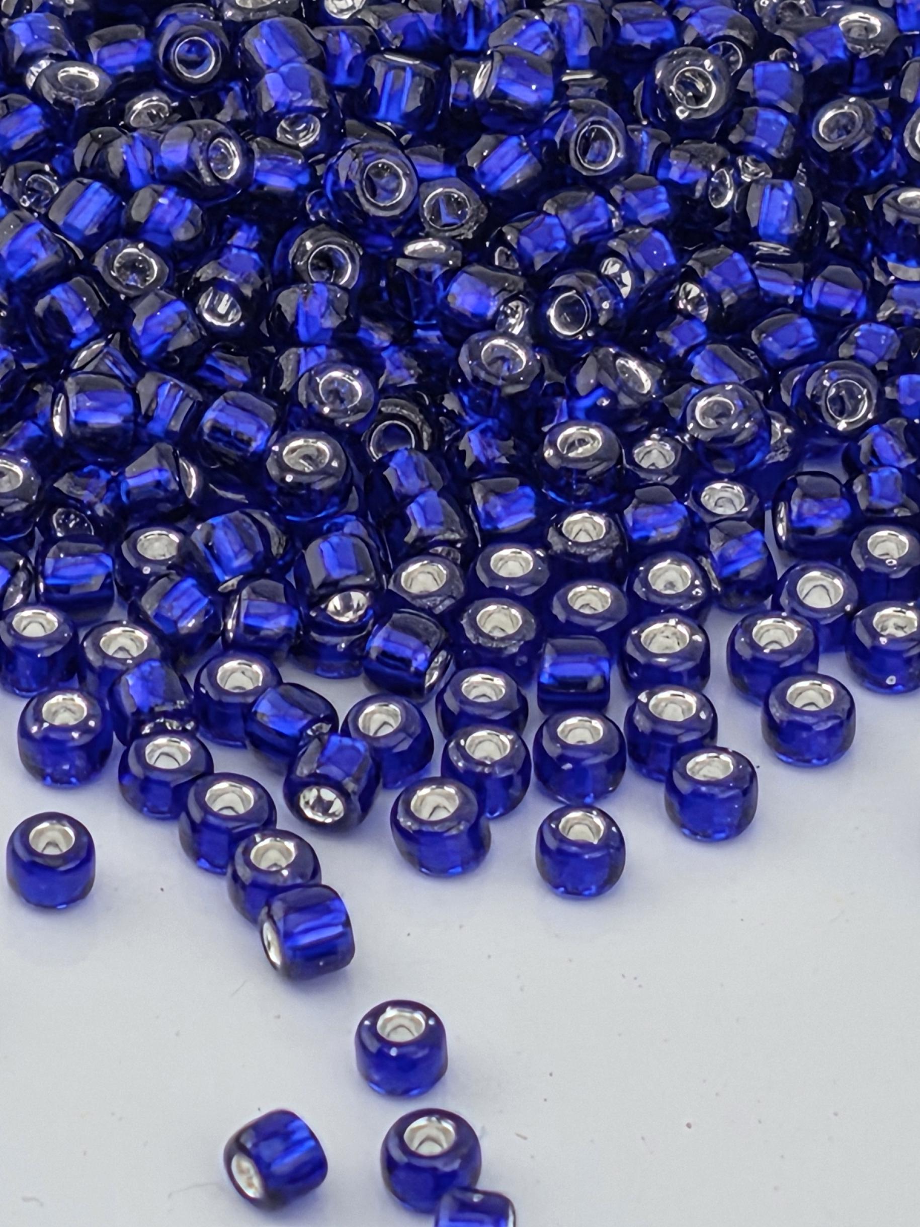 A close-up image of numerous blue and silver beads scattered on a white surface.