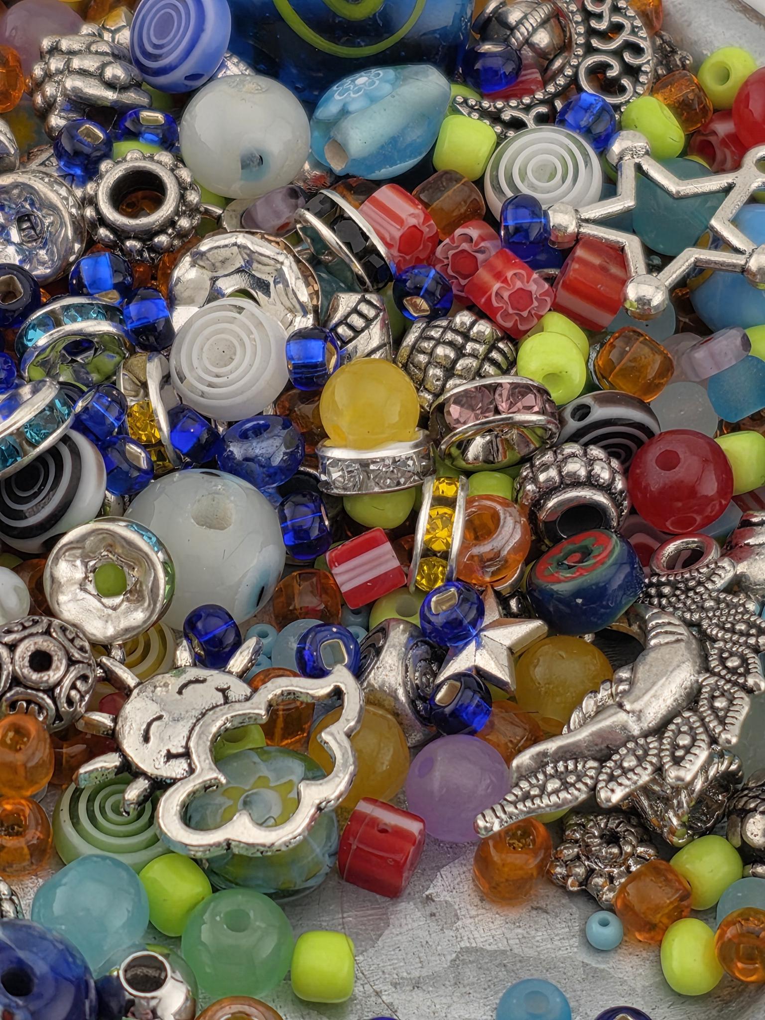 A colorful assortment of beads, charms, and other decorative items, including glass beads, metal charms, and other embellishments, are scattered across the image.