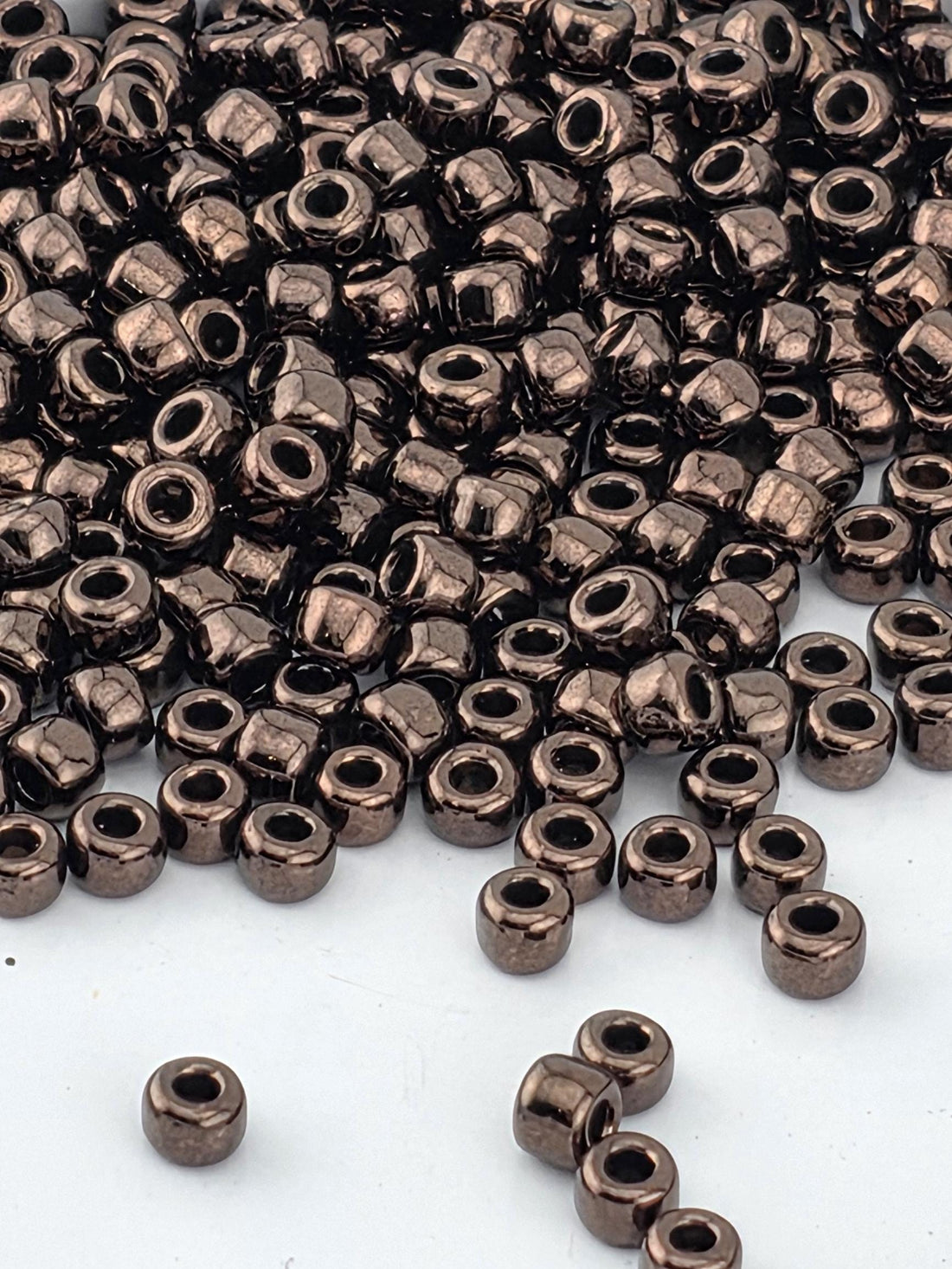 a large pile of small, shiny, metallic beads scattered on a white surface.