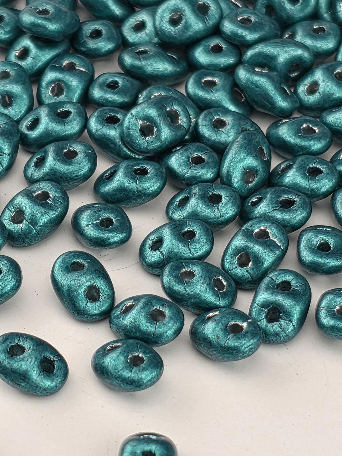 a collection of turquoise-colored beads scattered across a white background.