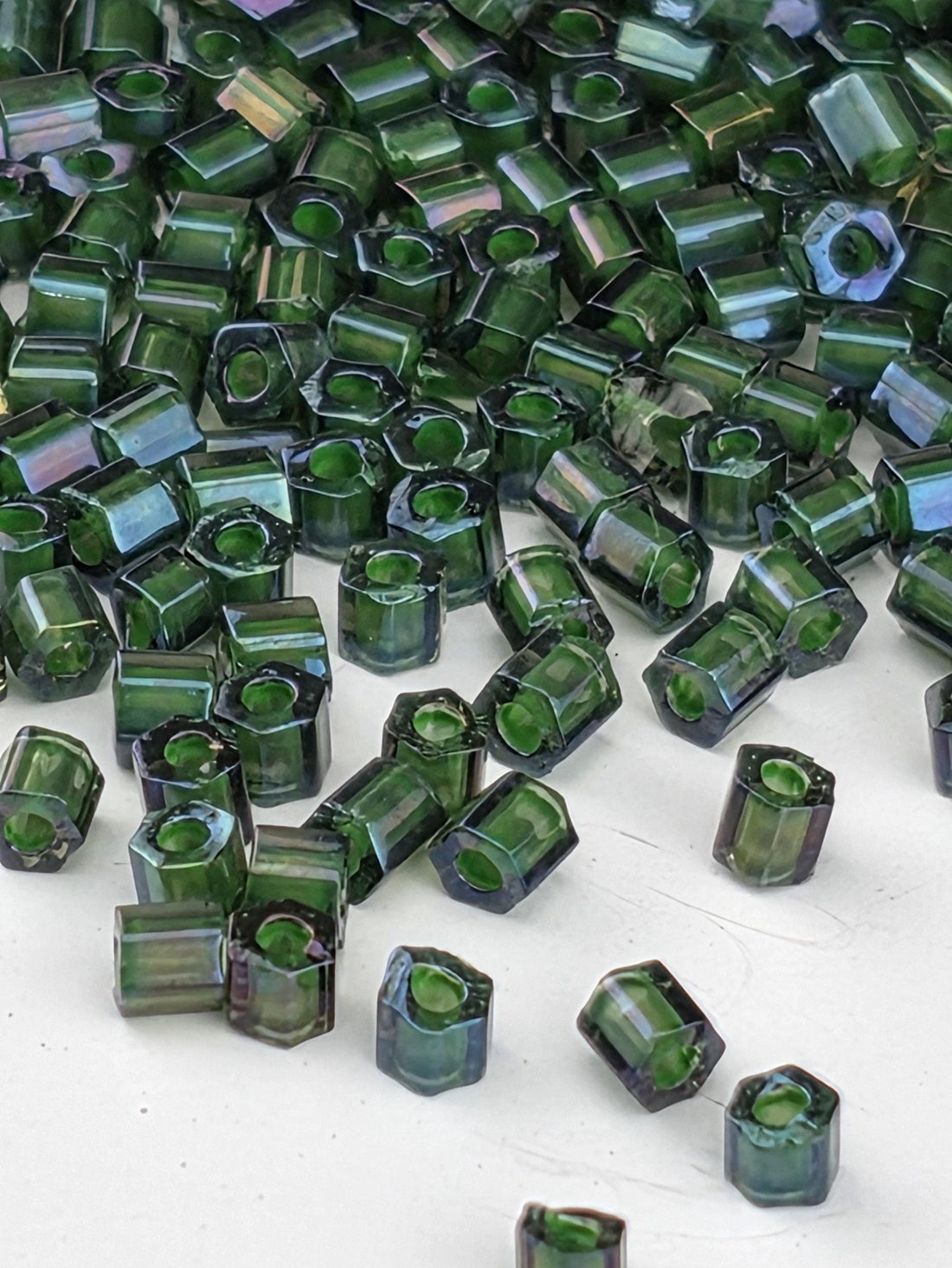 a close-up view of numerous green glass beads scattered on a white surface.