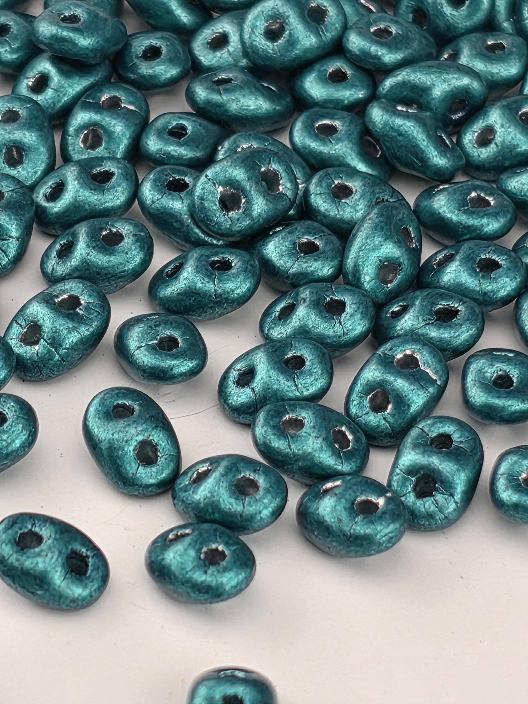 a collection of small, shiny blue beads scattered across a white surface.