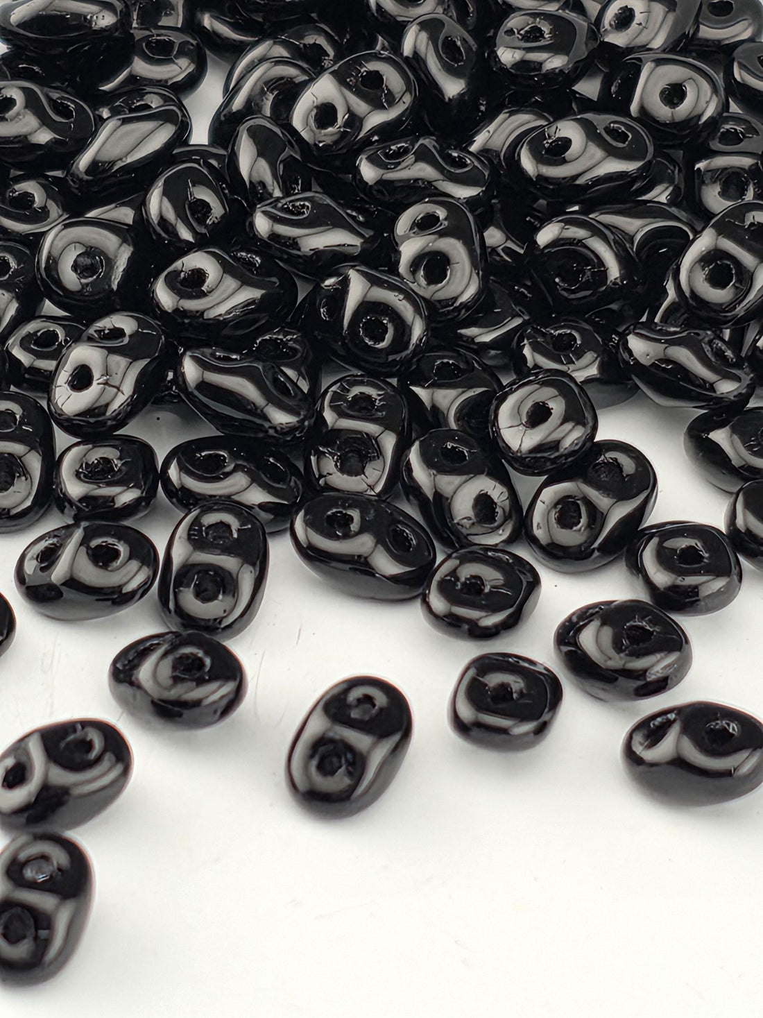 a collection of black beads scattered on a white background.