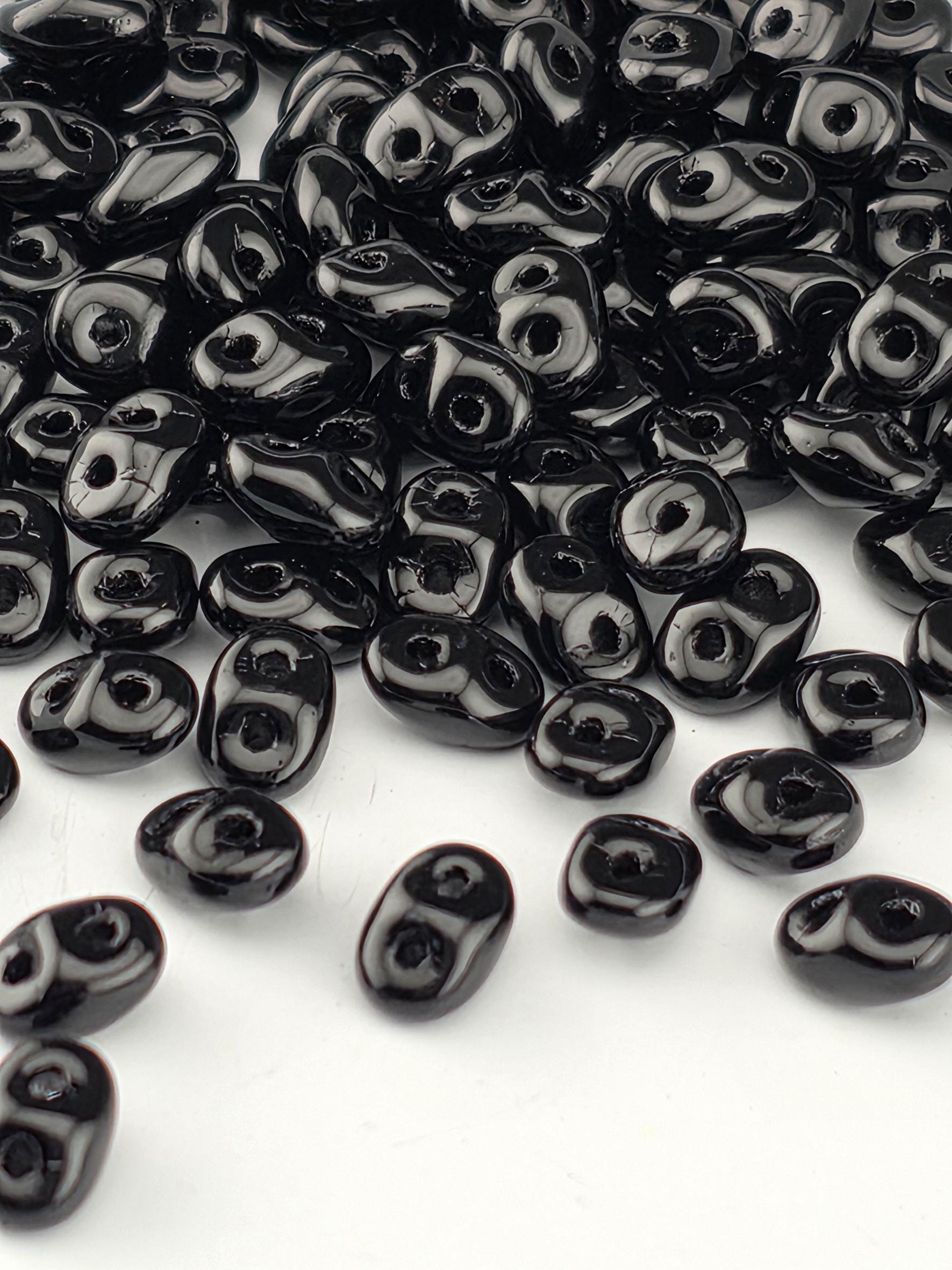a collection of black beads scattered on a white background.