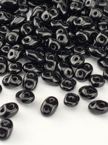 a collection of black beads scattered on a white background.