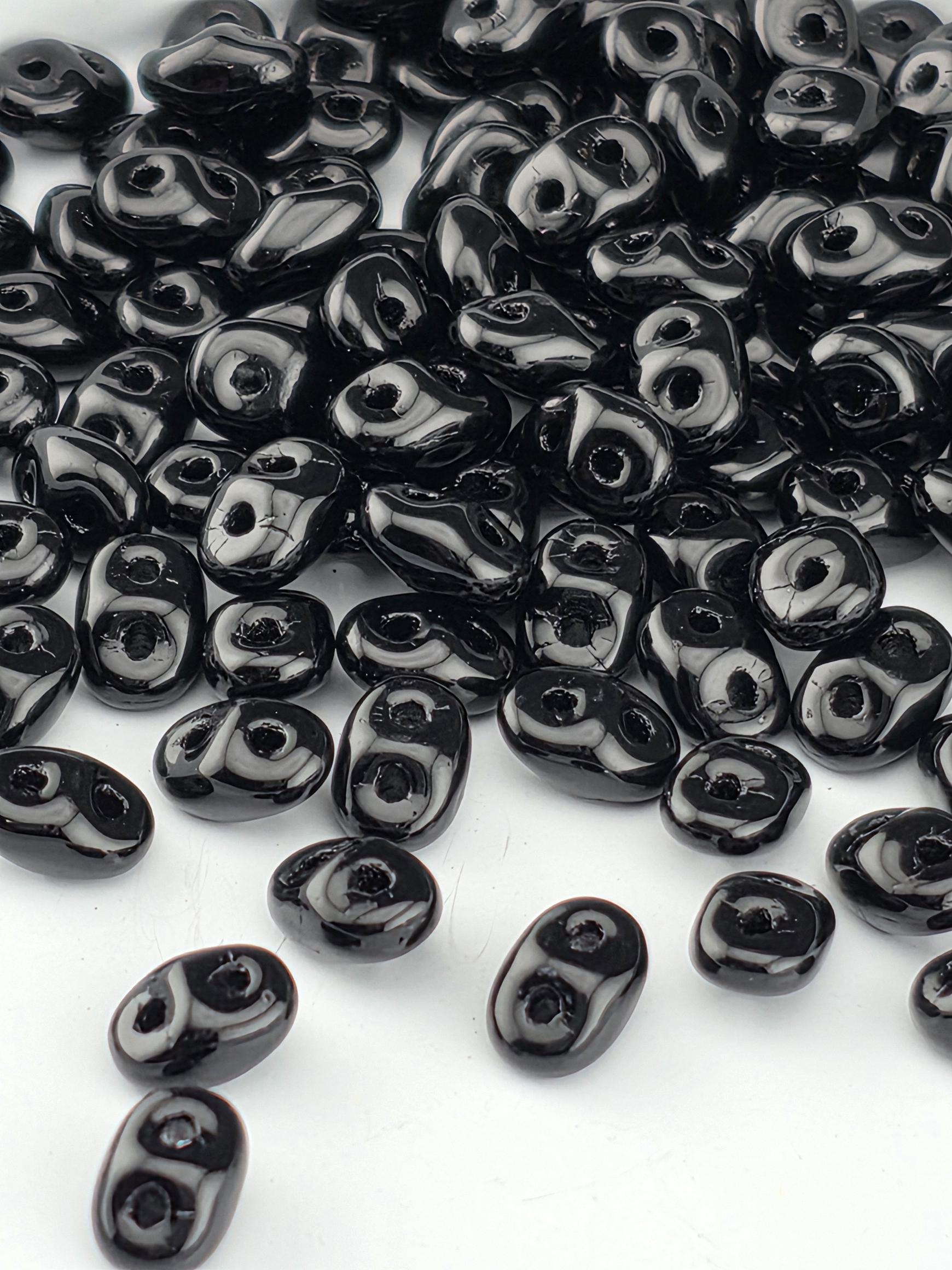 a collection of black beads scattered on a white background.