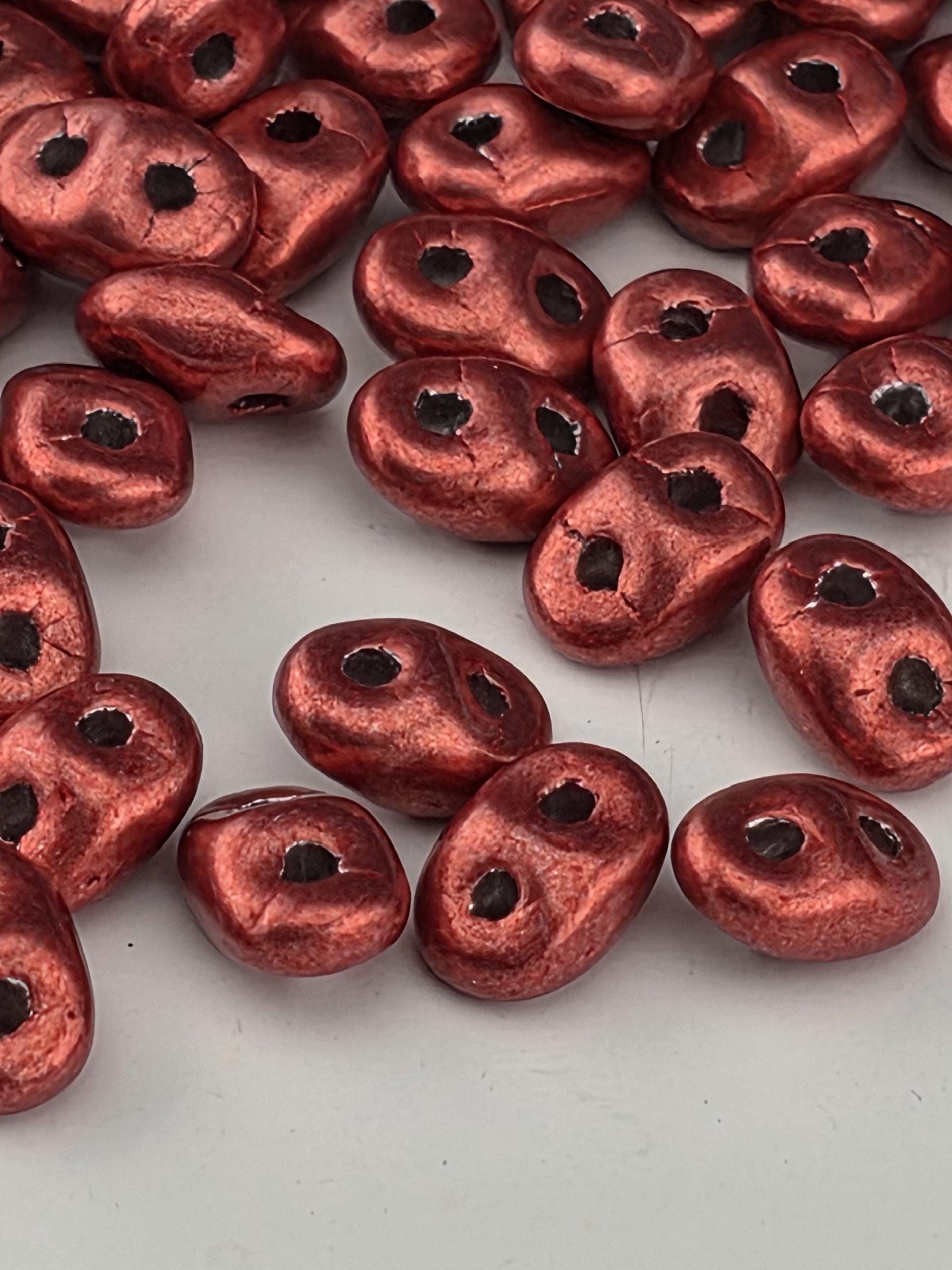 a collection of red, metallic beads scattered across a white surface.