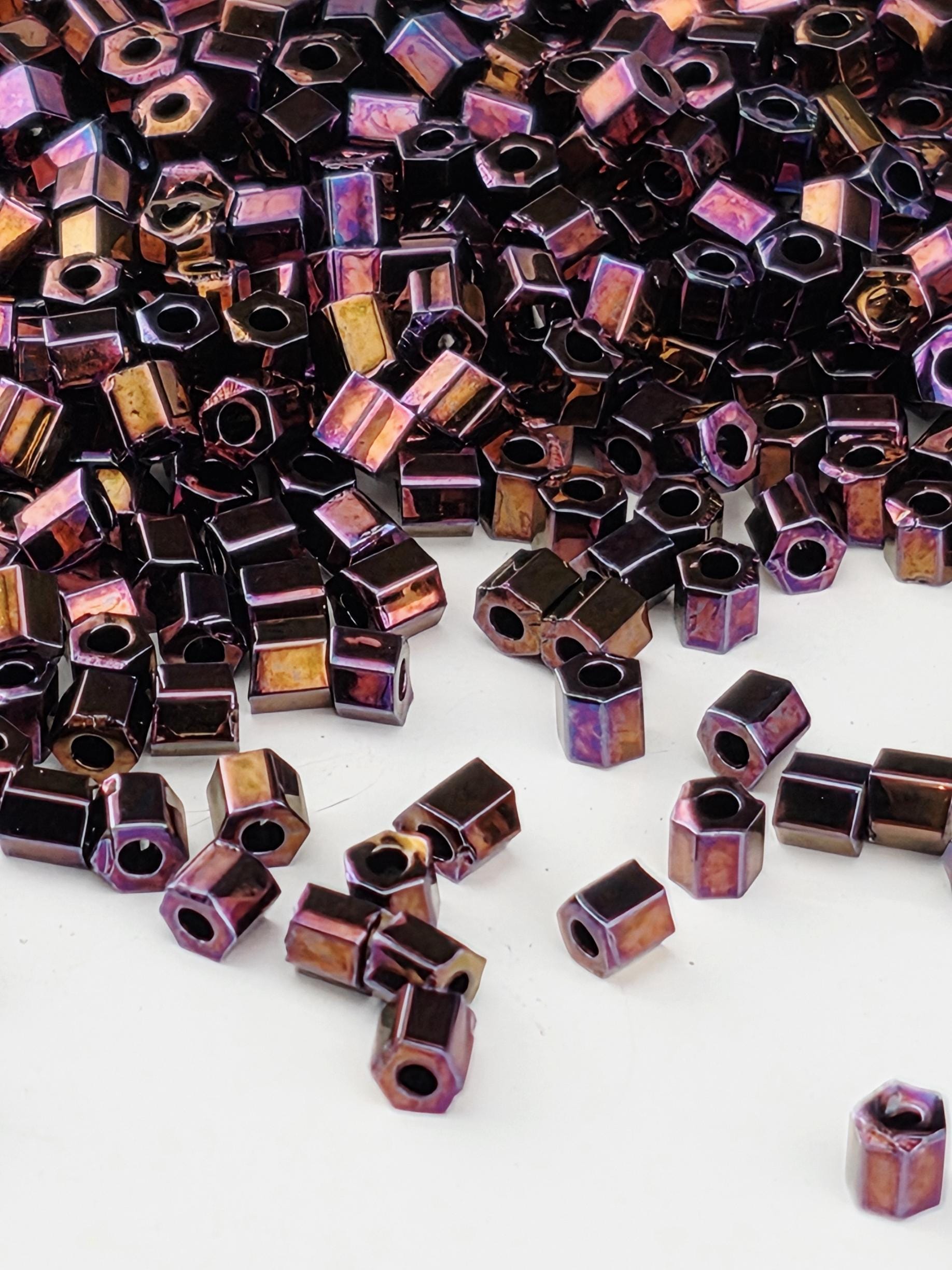 a close-up view of numerous small, square-shaped metal pieces in various shades of purple and brown, scattered across a white background.