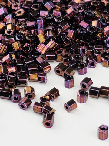 a close-up view of numerous small, square-shaped metal pieces in various shades of purple and brown, scattered across a white background.