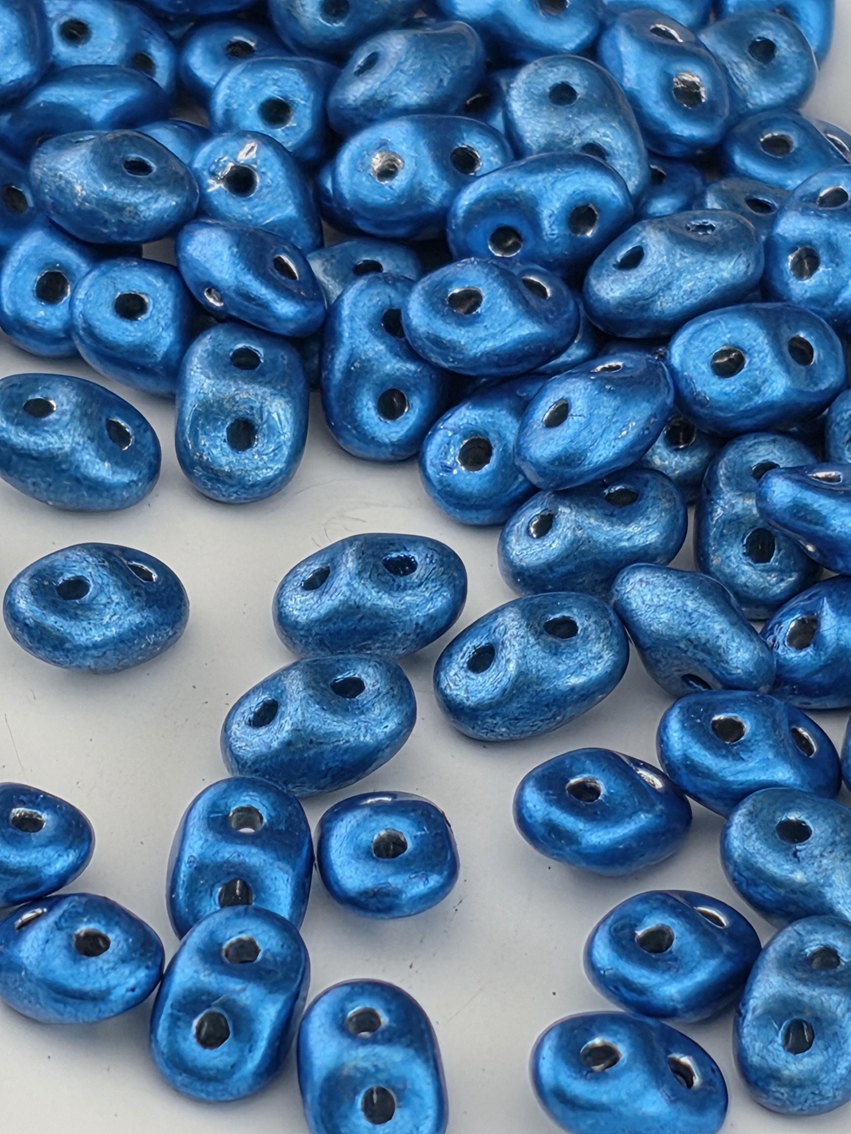 a collection of blue beads scattered across a surface, with some of the beads overlapping each other.